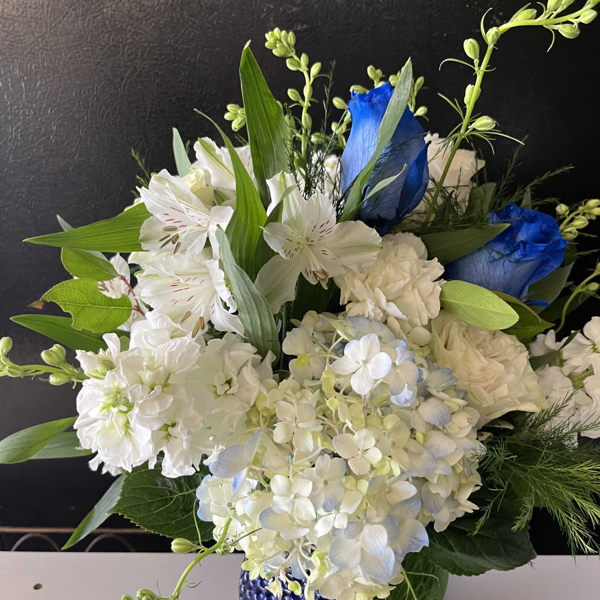 White and blue floral arrangement in a cobalt glass vase