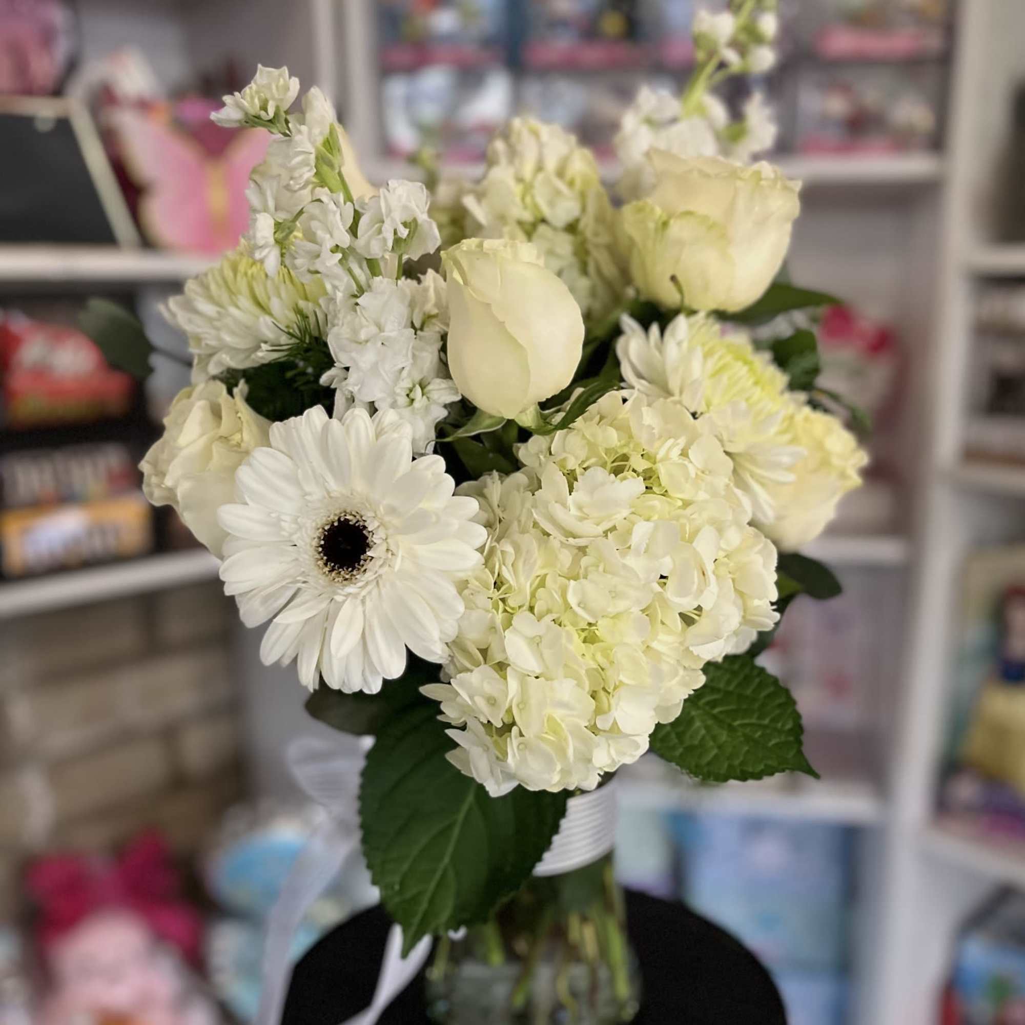 White flowers arranged in a glass vase with a ribbon