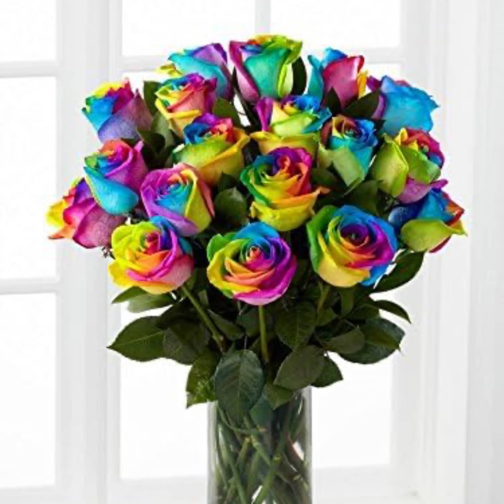 Rainbow-colored roses arranged in a clear glass vase
