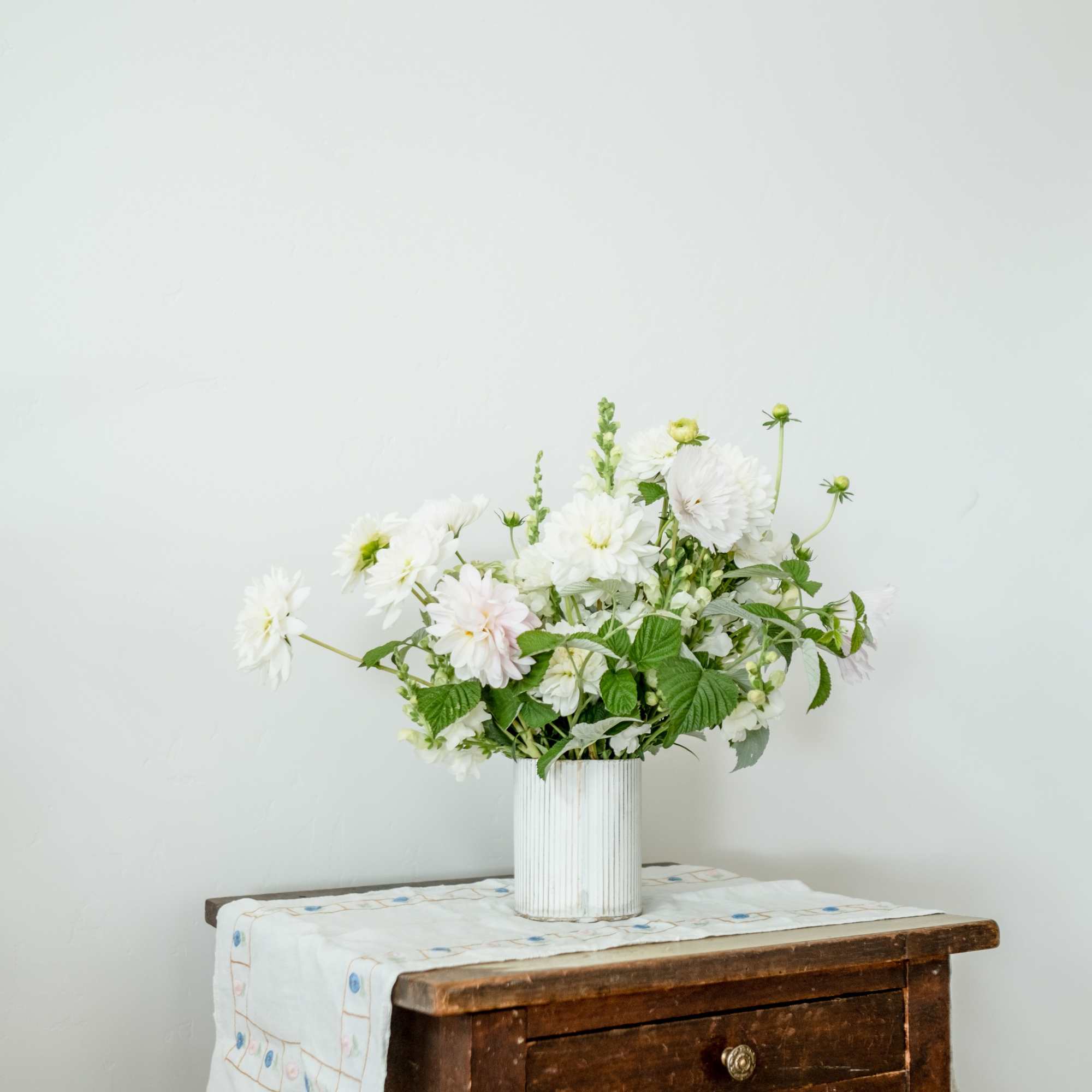 White floral arrangement in a ribbed vase on a wooden table