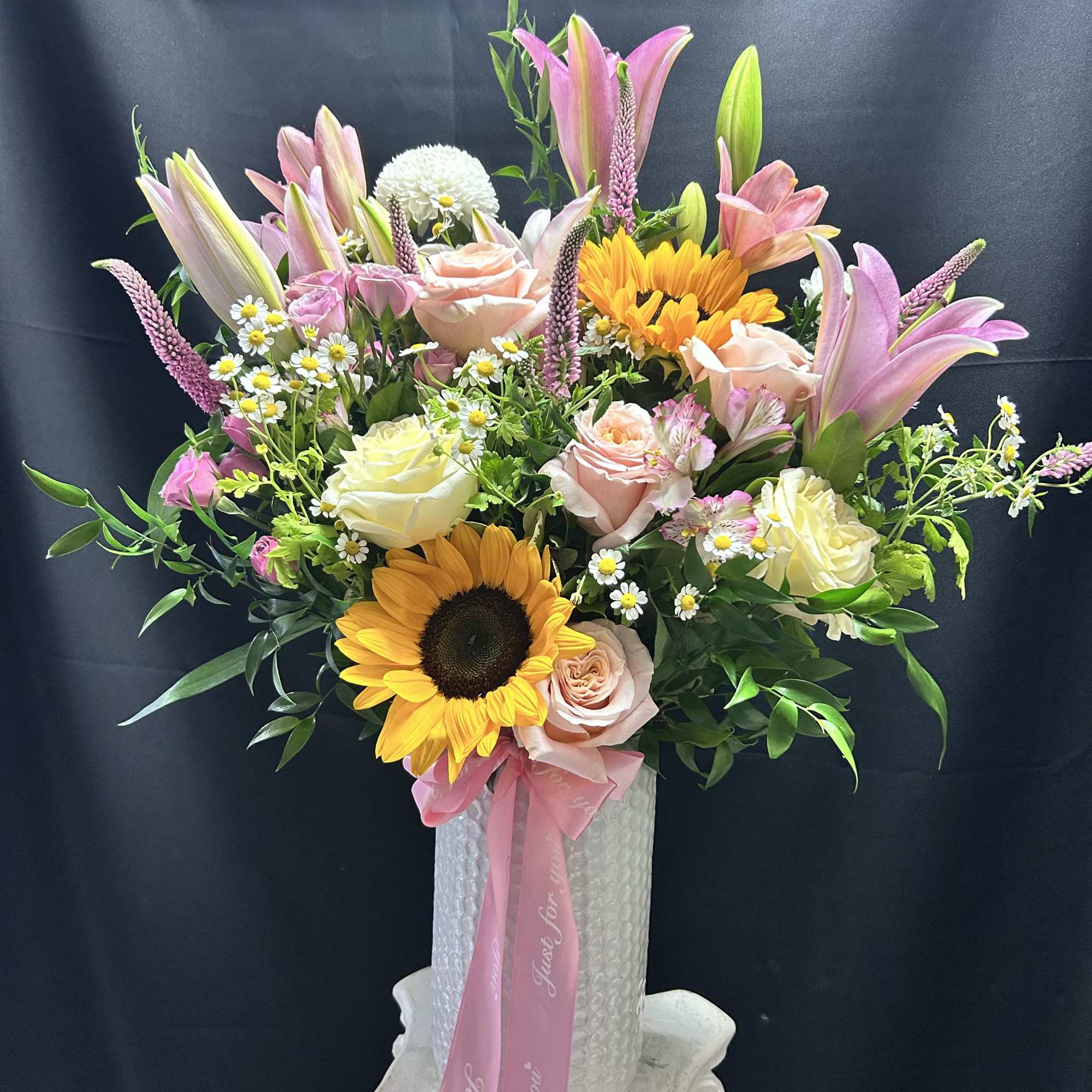 Sun-kissed sunflowers and tall pink lilies give this upright mixed flower arrangement