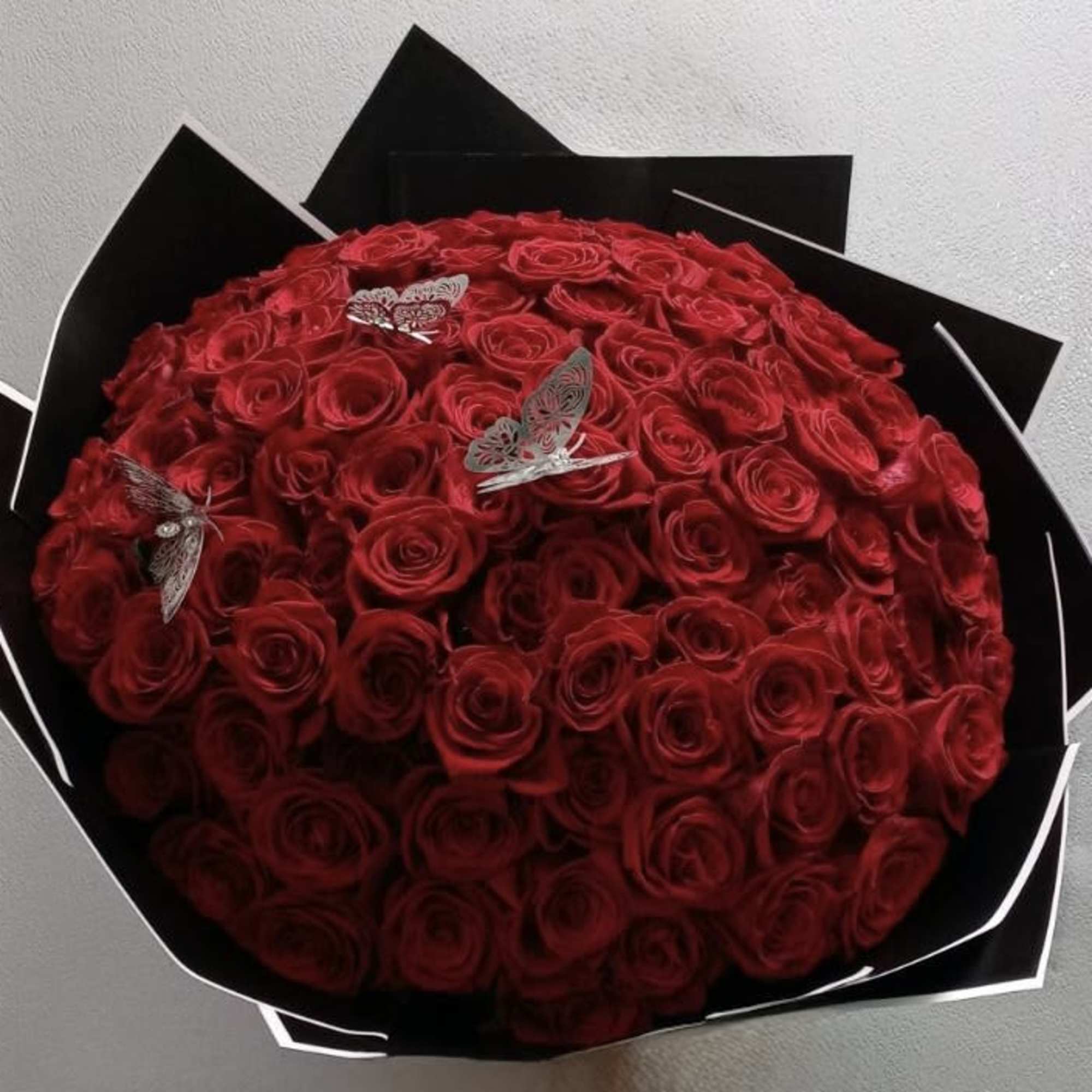 100 roses arranged into a round bouquet with the color paper of