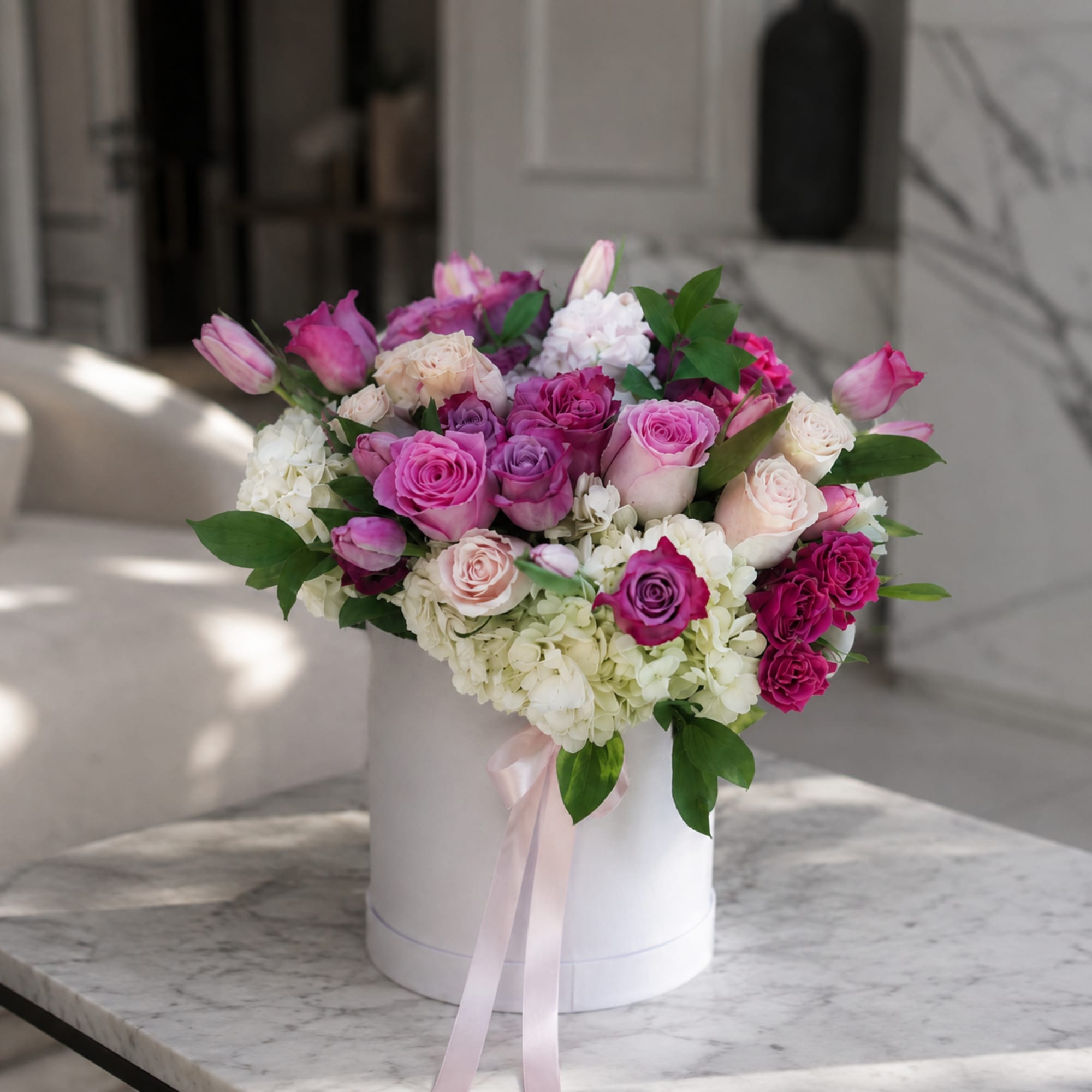 Lavender and bright pink blooms spill from a crisp white hatbox in