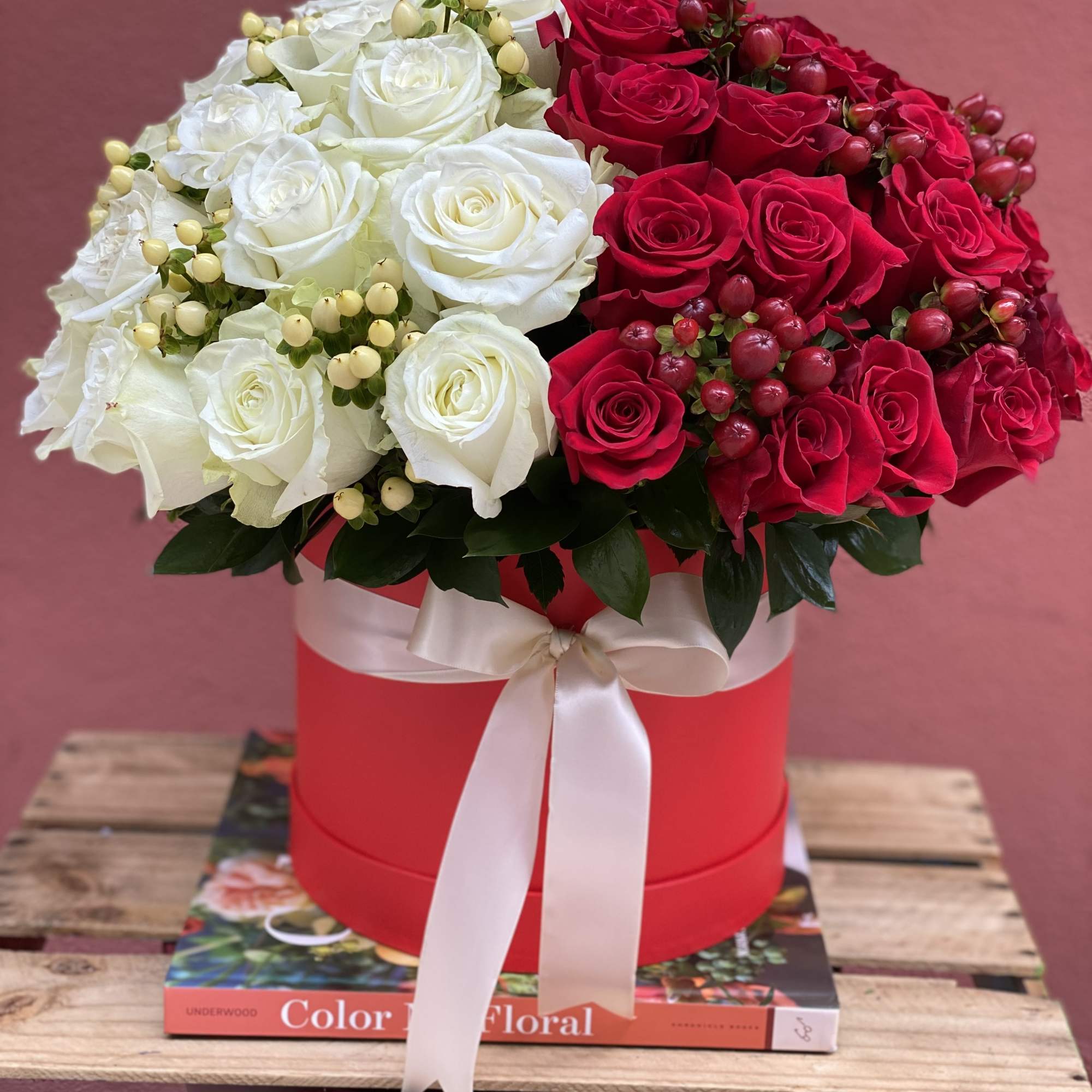 Red and white rose arrangement in a round hat box with a ribbon