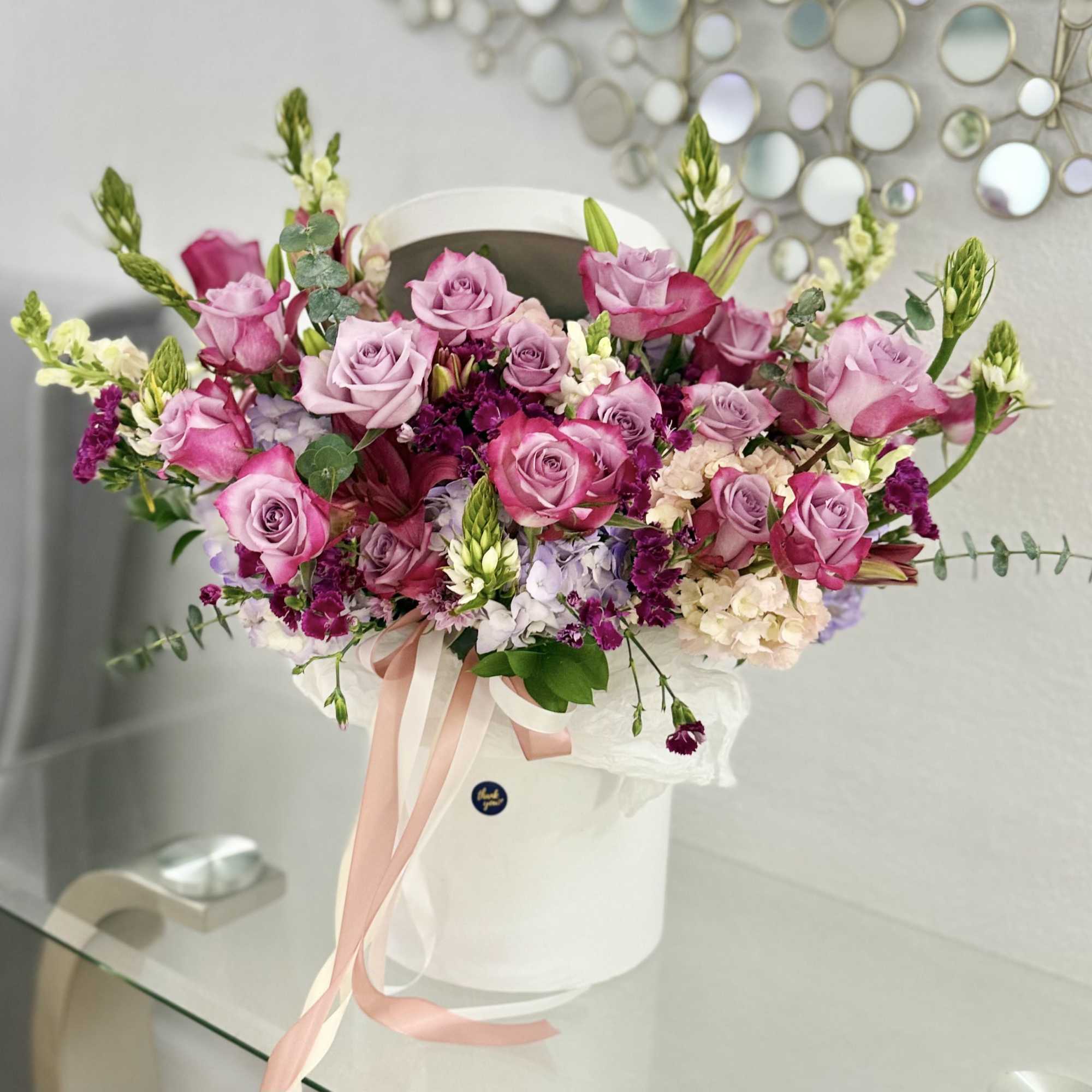 A lush cluster of pink and lavender roses crowned with pale hydrangea