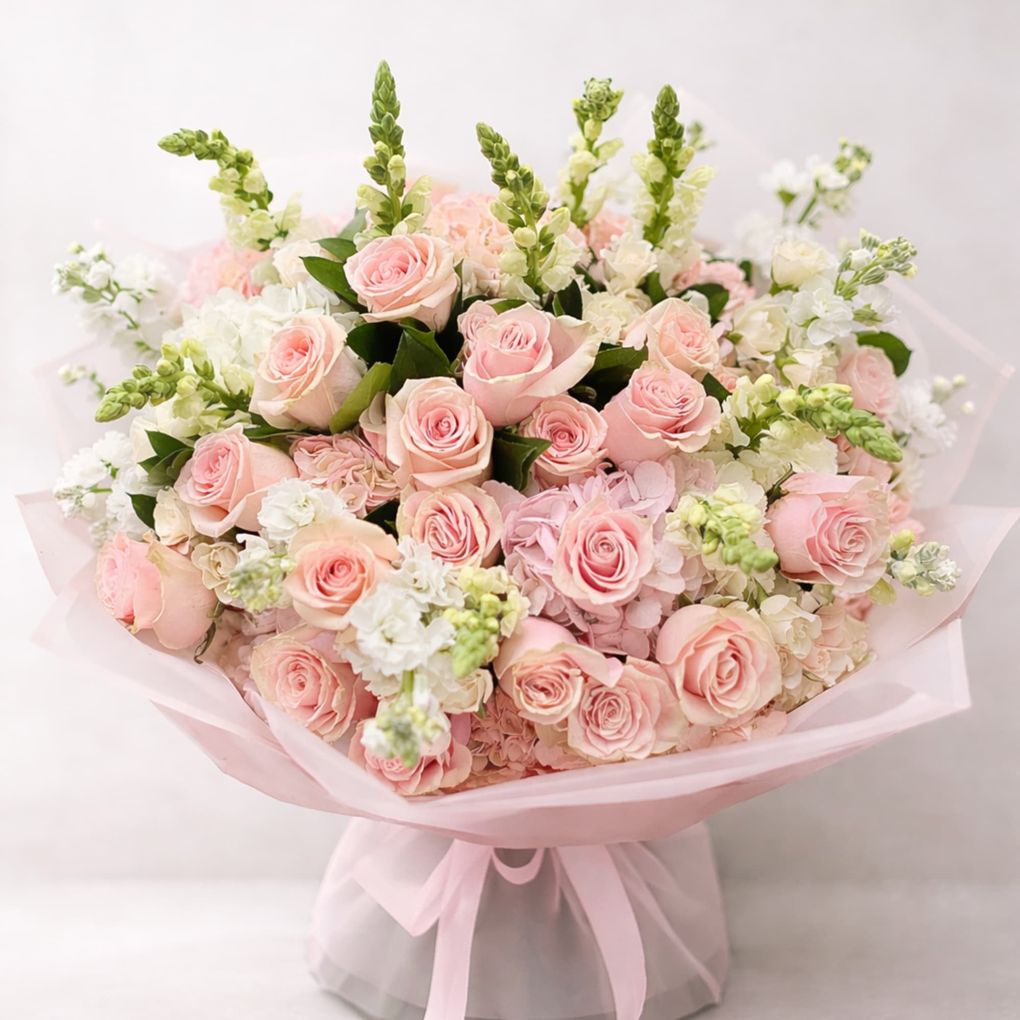 A cloud of pale pink roses takes center stage in this hand-tied