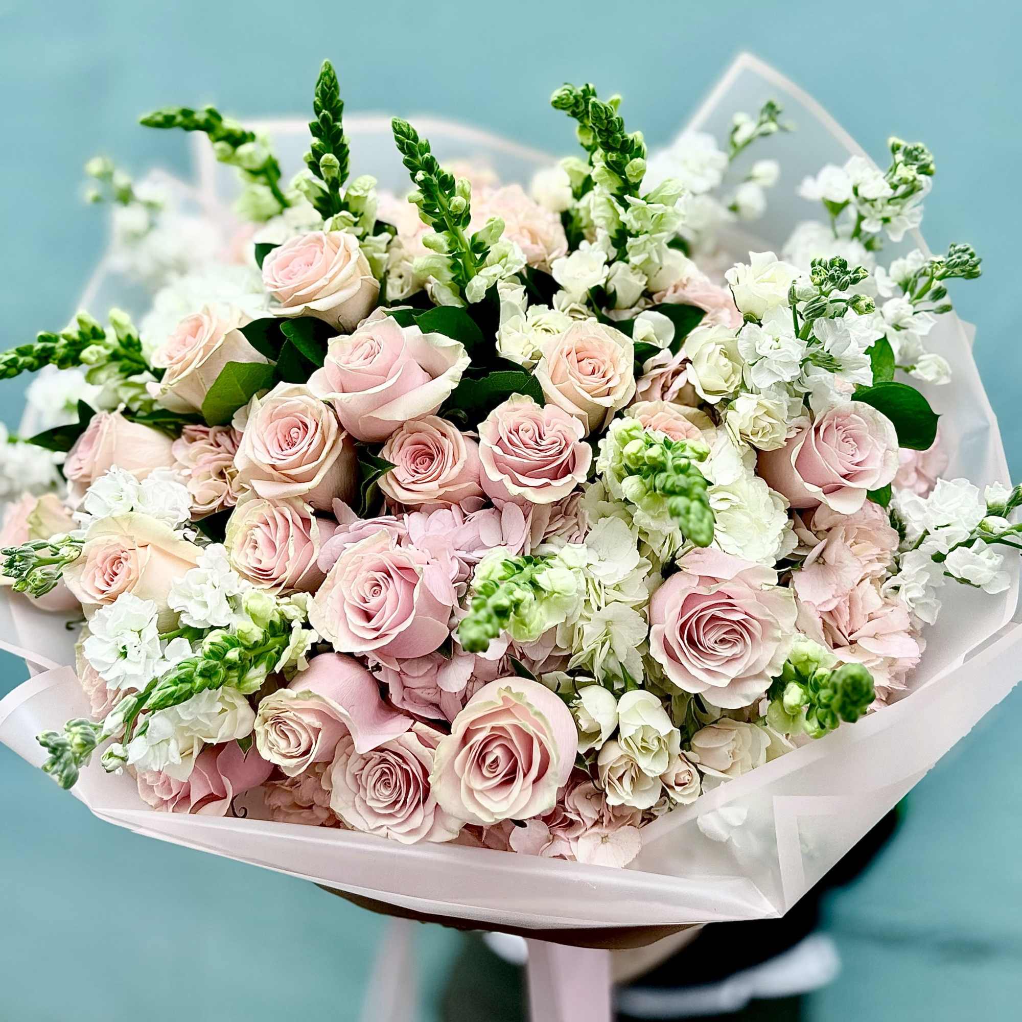 A cloud of pale pink roses takes center stage in this hand-tied
