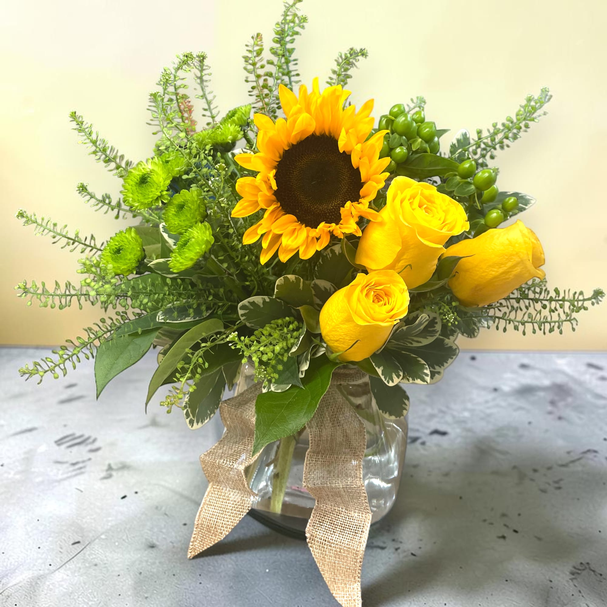 Radiant yellow roses and cheerful sunflowers, complemented by vibrant green mums, create