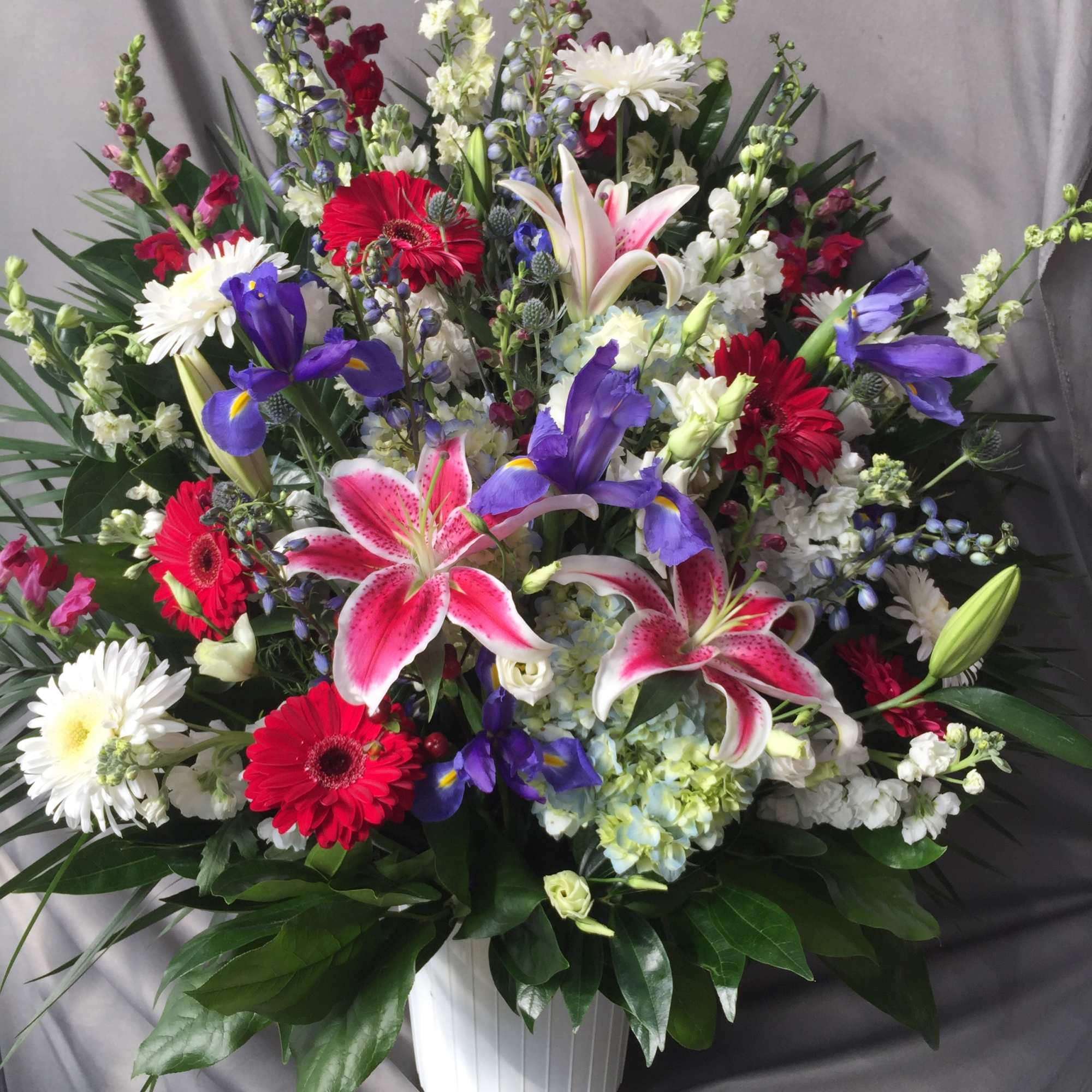 Mixed bouquet in a white vase with lilies, gerberas, irises, and daisies