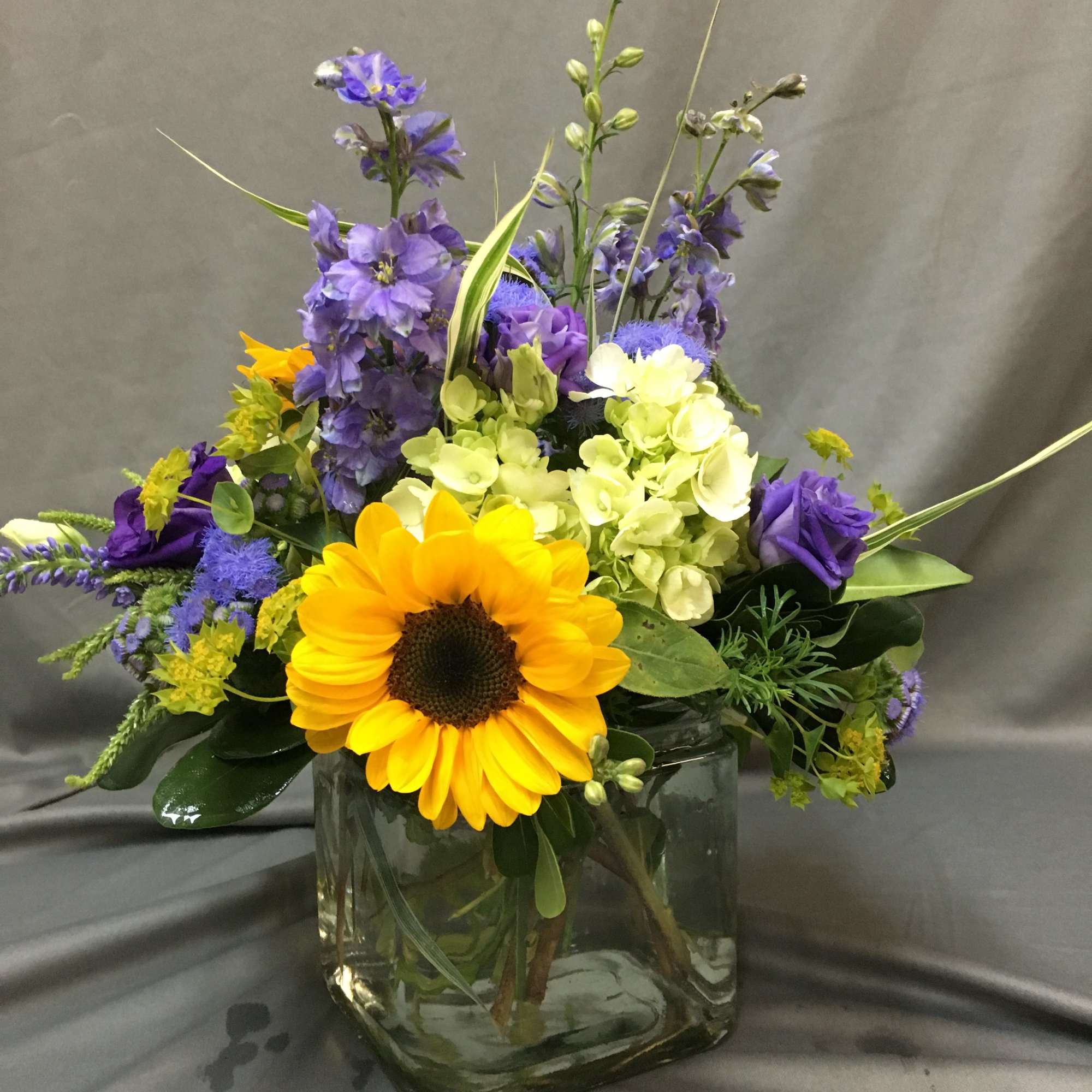 Mixed bouquet with a sunflower and purple blooms in a glass vase