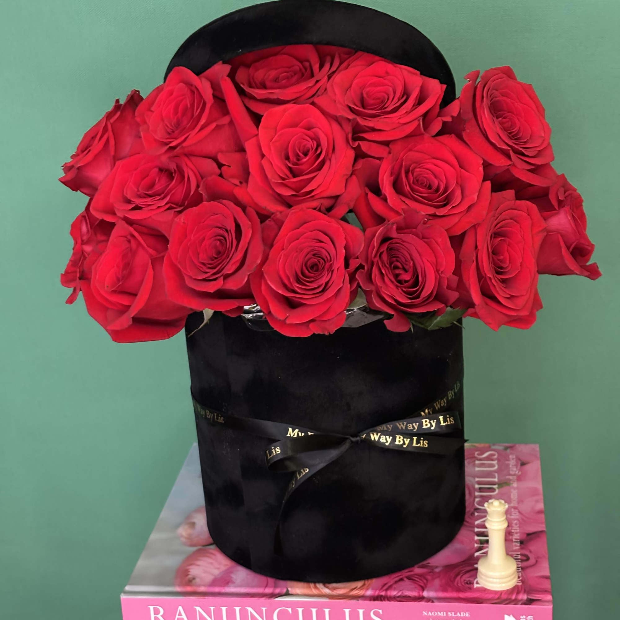 Red roses arranged in a black hatbox with a ribbon