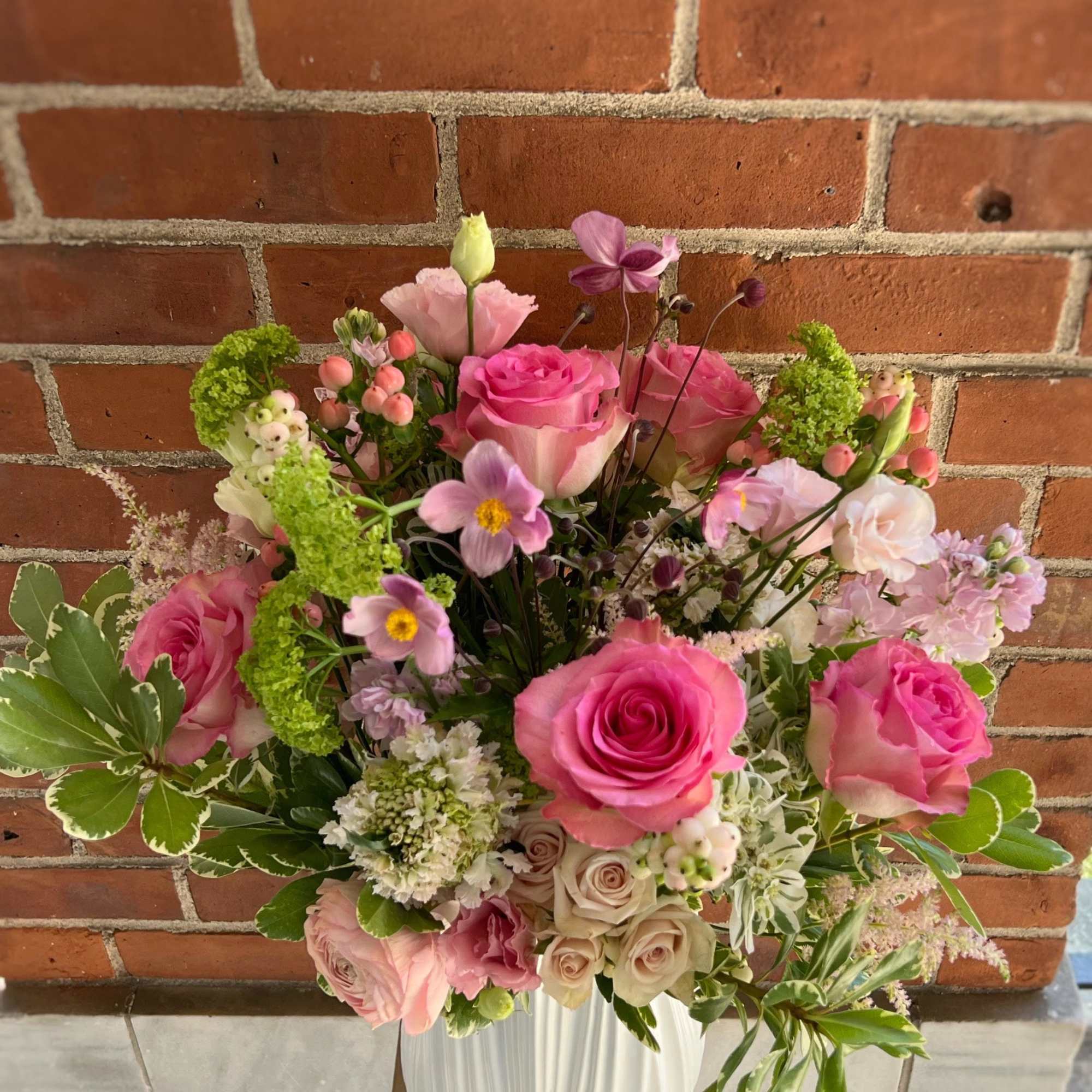Pink rose arrangement in a white vase with mixed pastel blooms