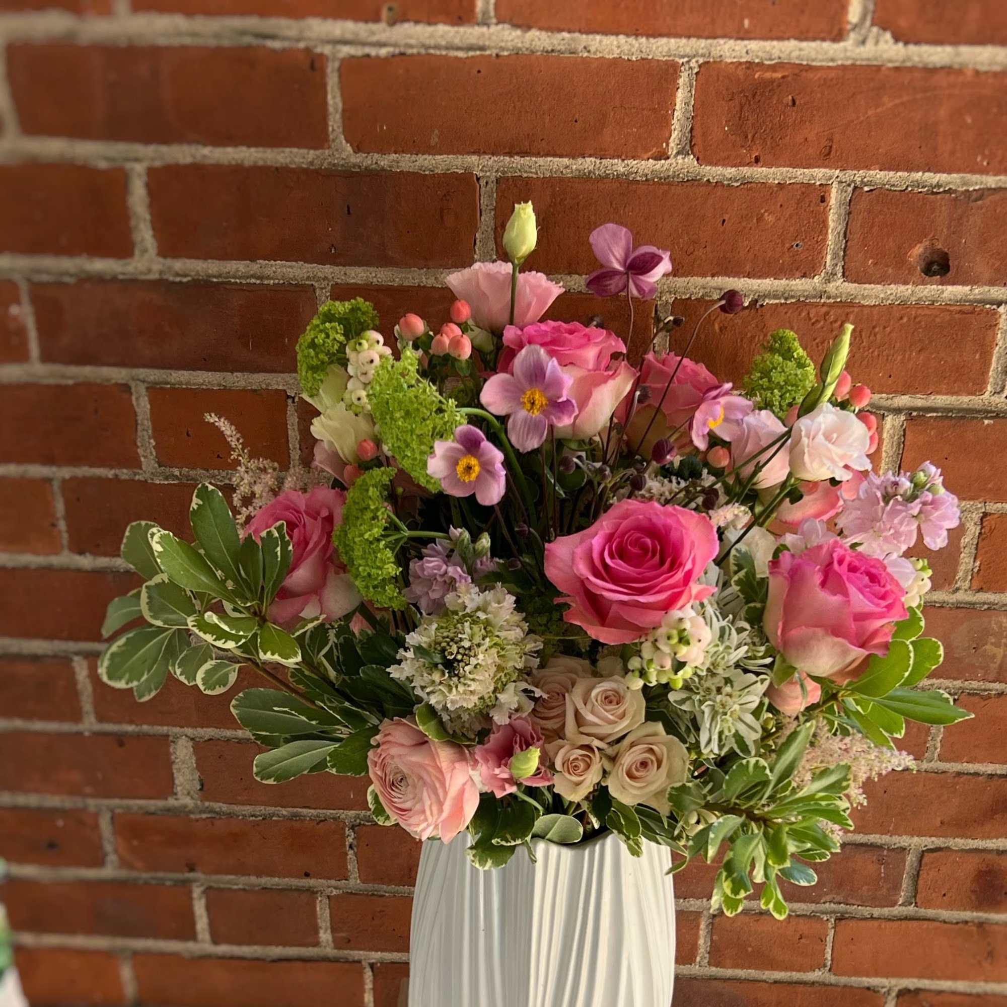 Pink and purple mixed flower arrangement in a white vase