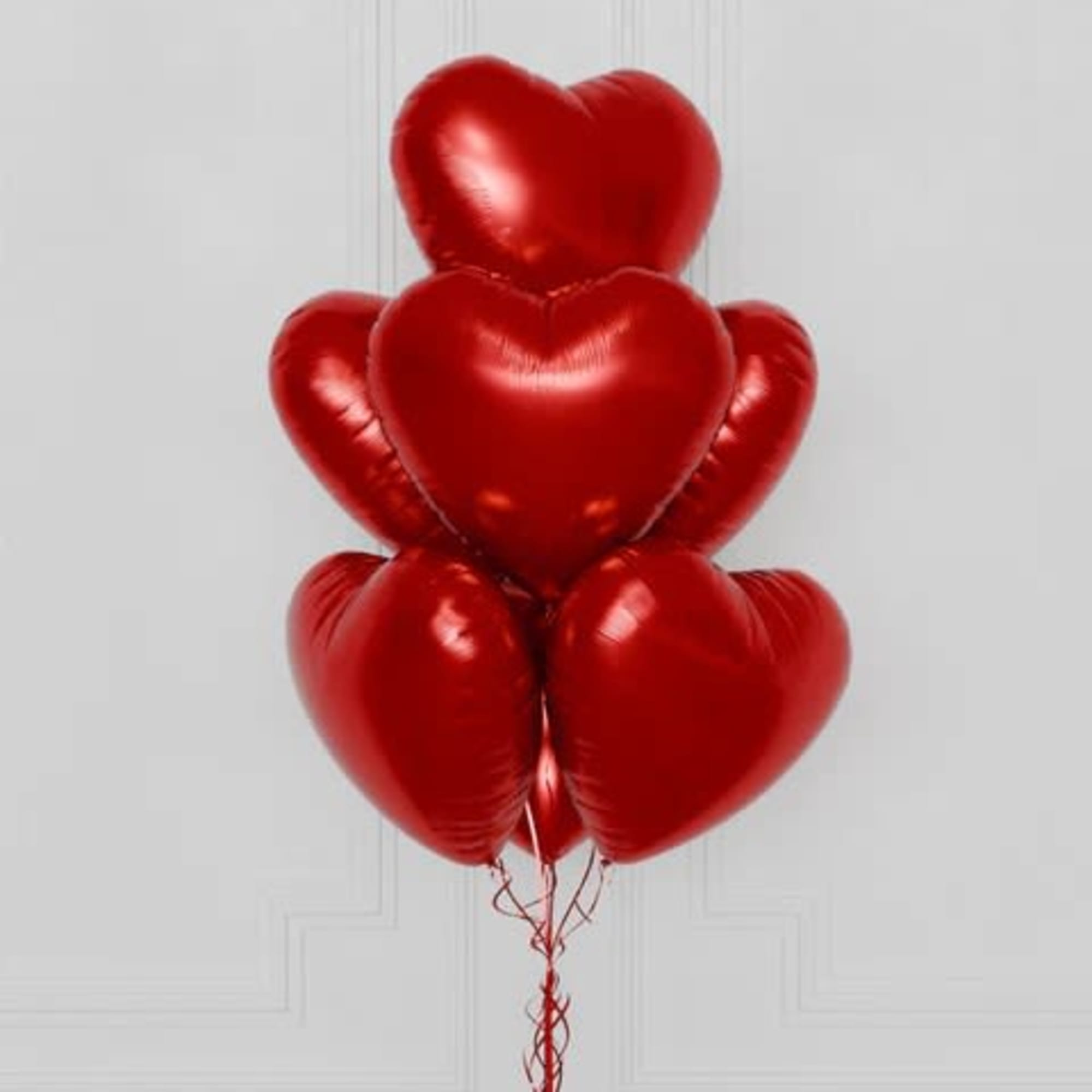 Cluster of red heart-shaped balloons tied together with curling ribbons
