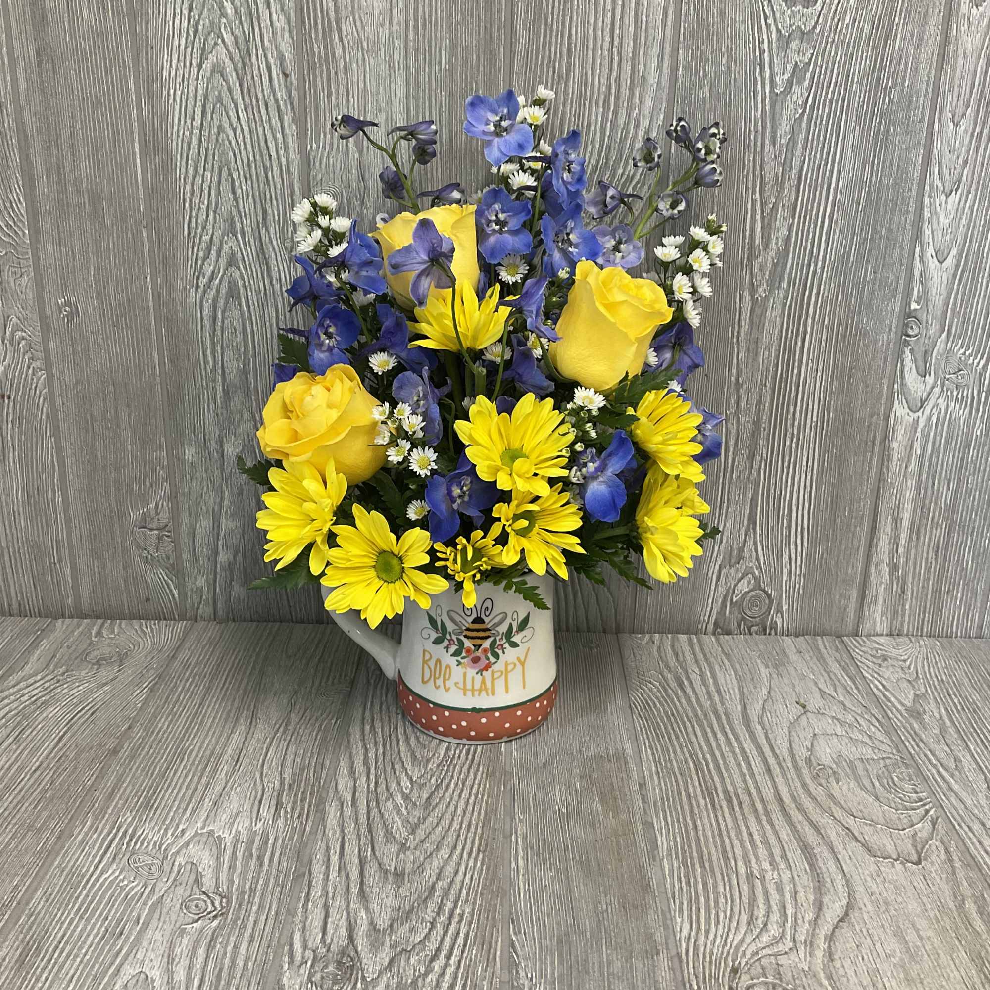 Yellow roses and blue flowers in a bee-themed mug
