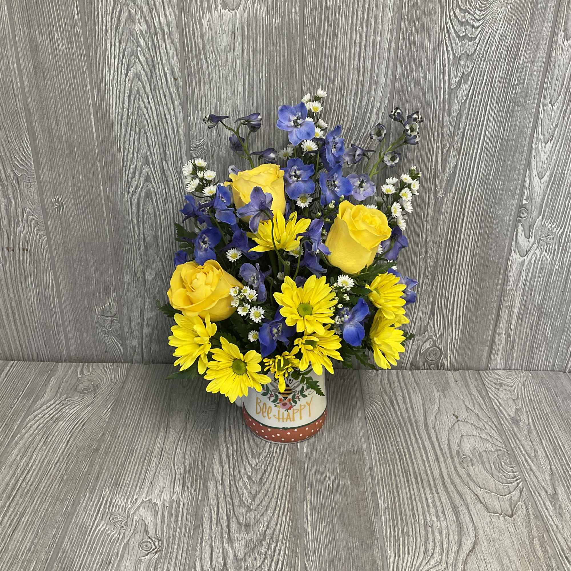 Yellow roses and blue flowers in a decorative tin container
