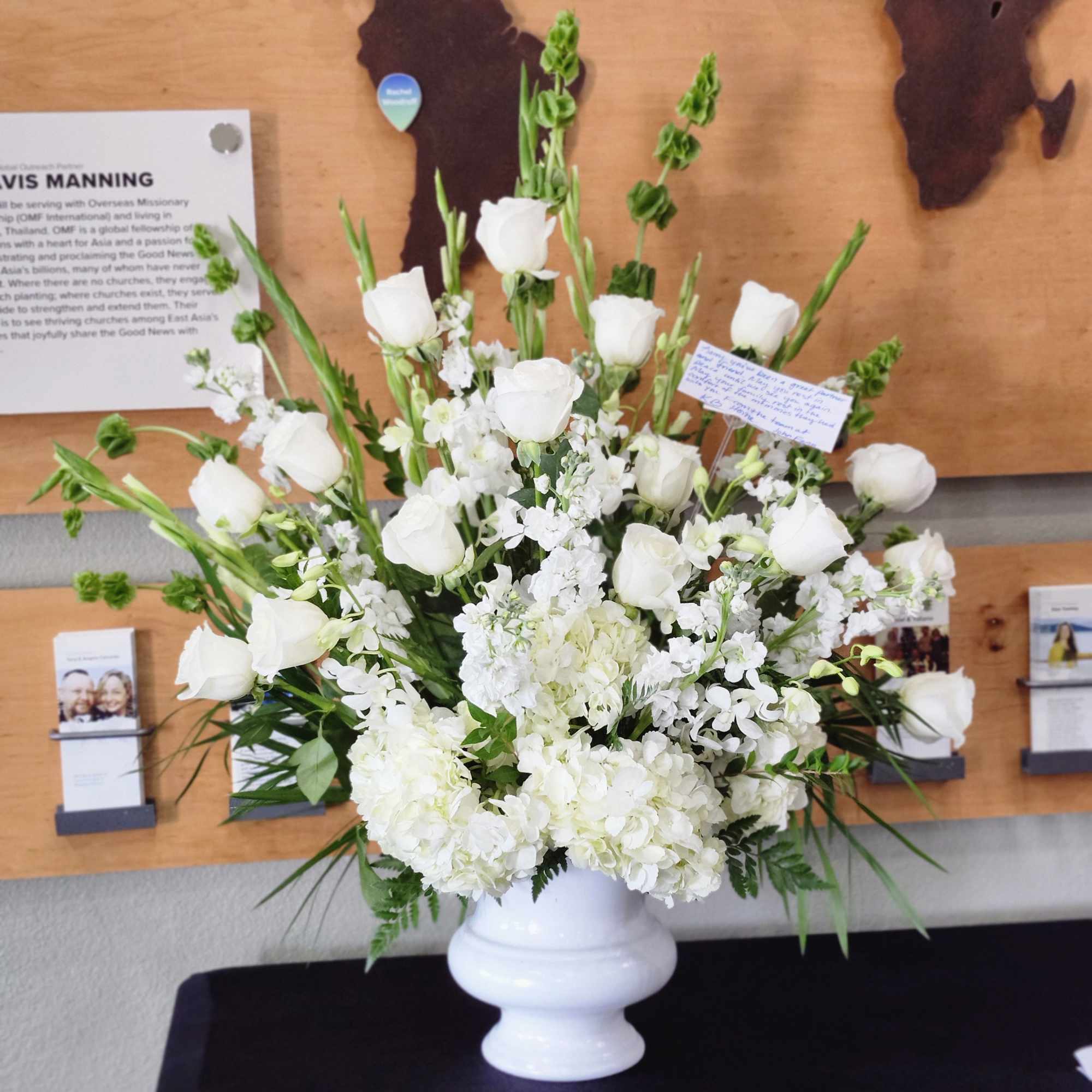 White floral arrangement in a white vase with roses and hydrangeas