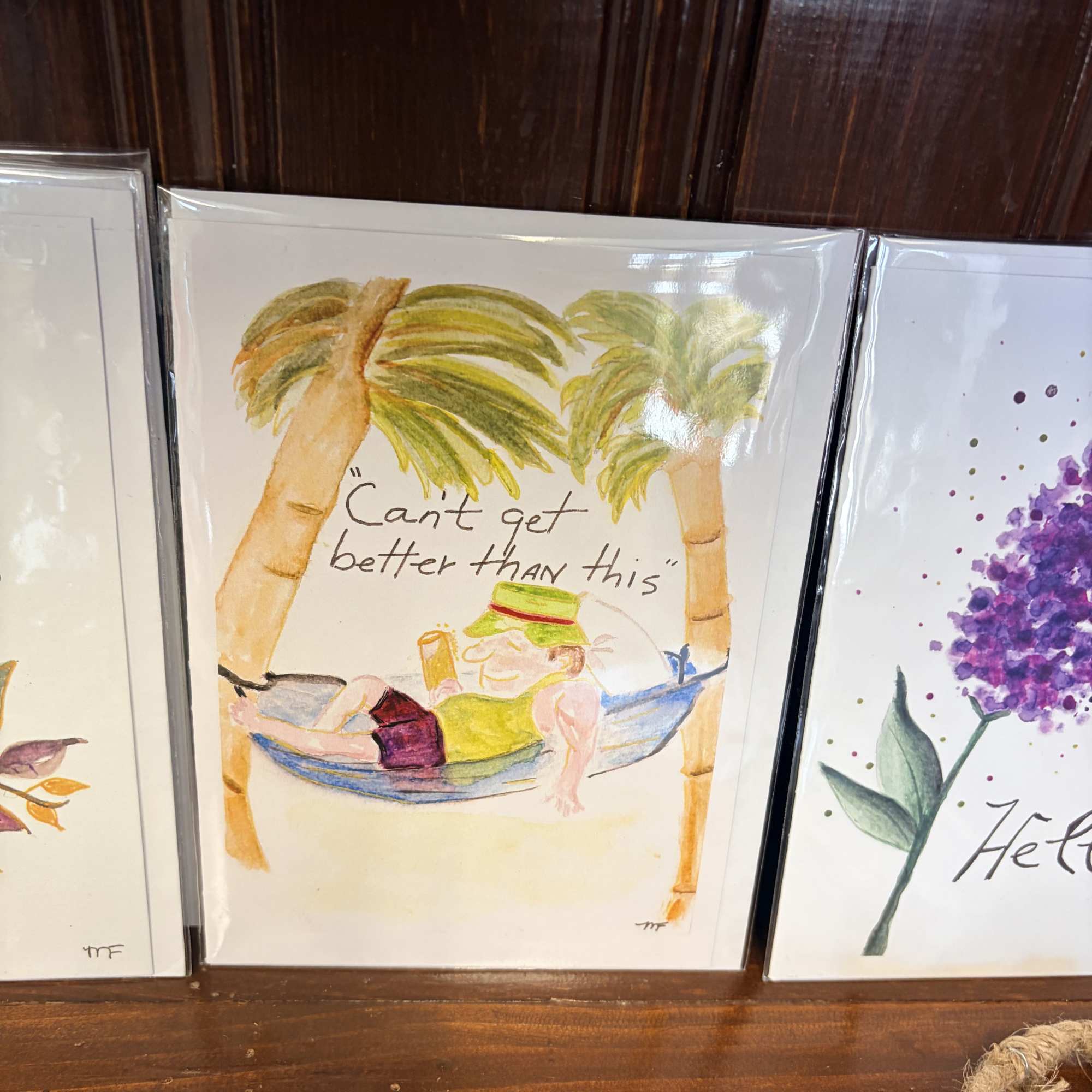Hand-painted card of a person relaxing in a hammock between palm trees