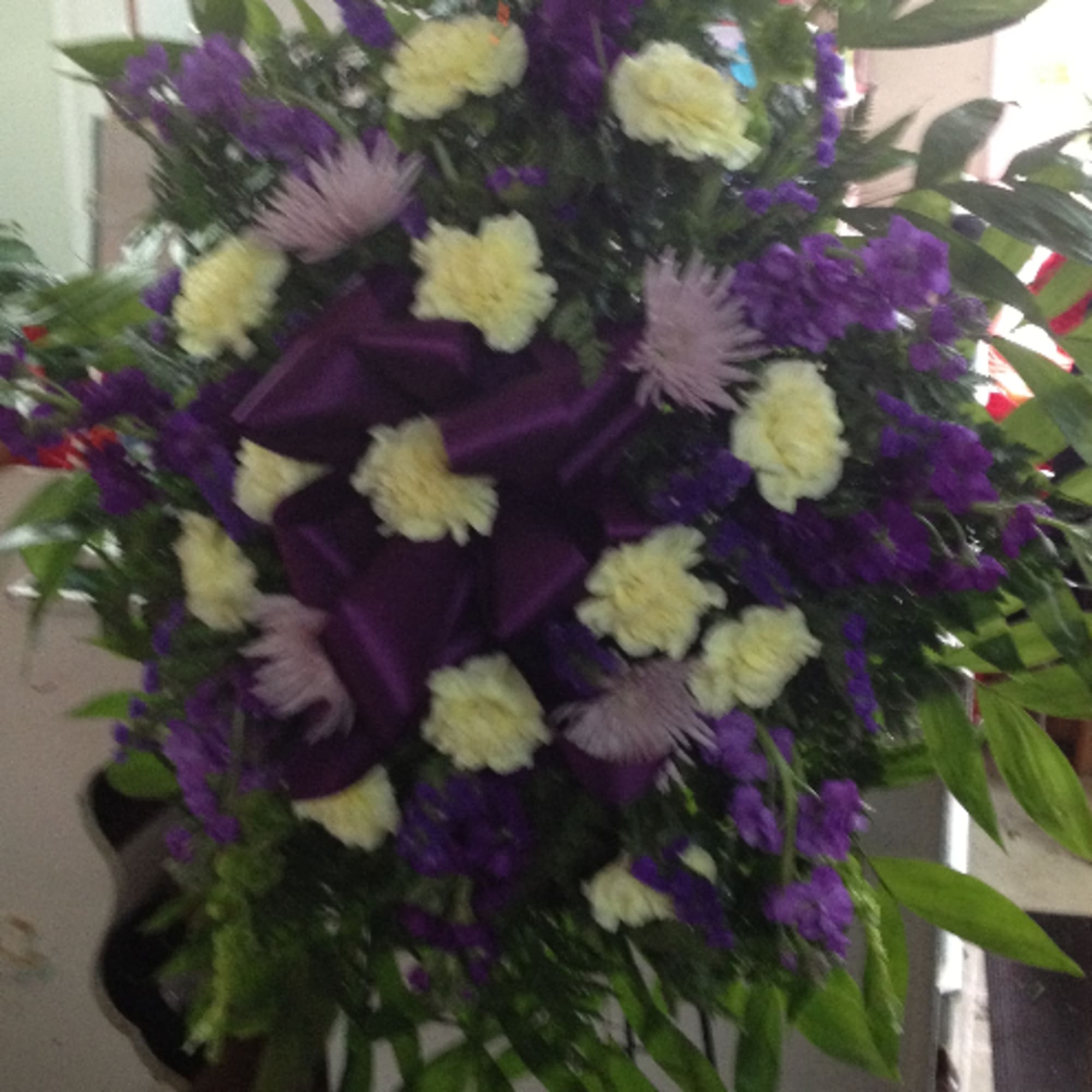 Purple and cream floral standing spray with dark ribbon accents
