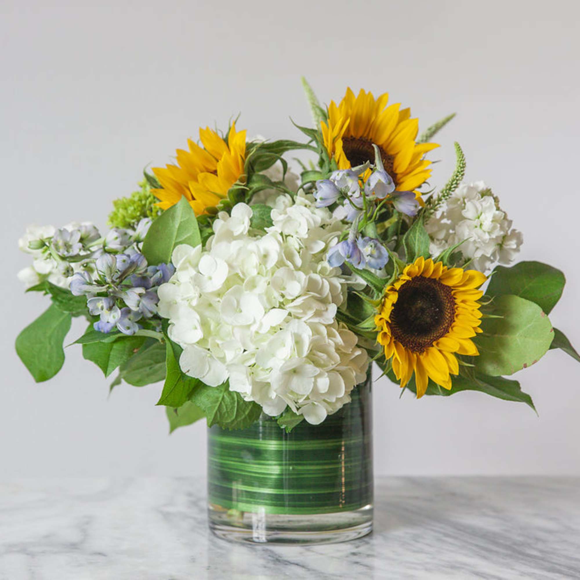 Sunflowers and white hydrangeas in a glass vase