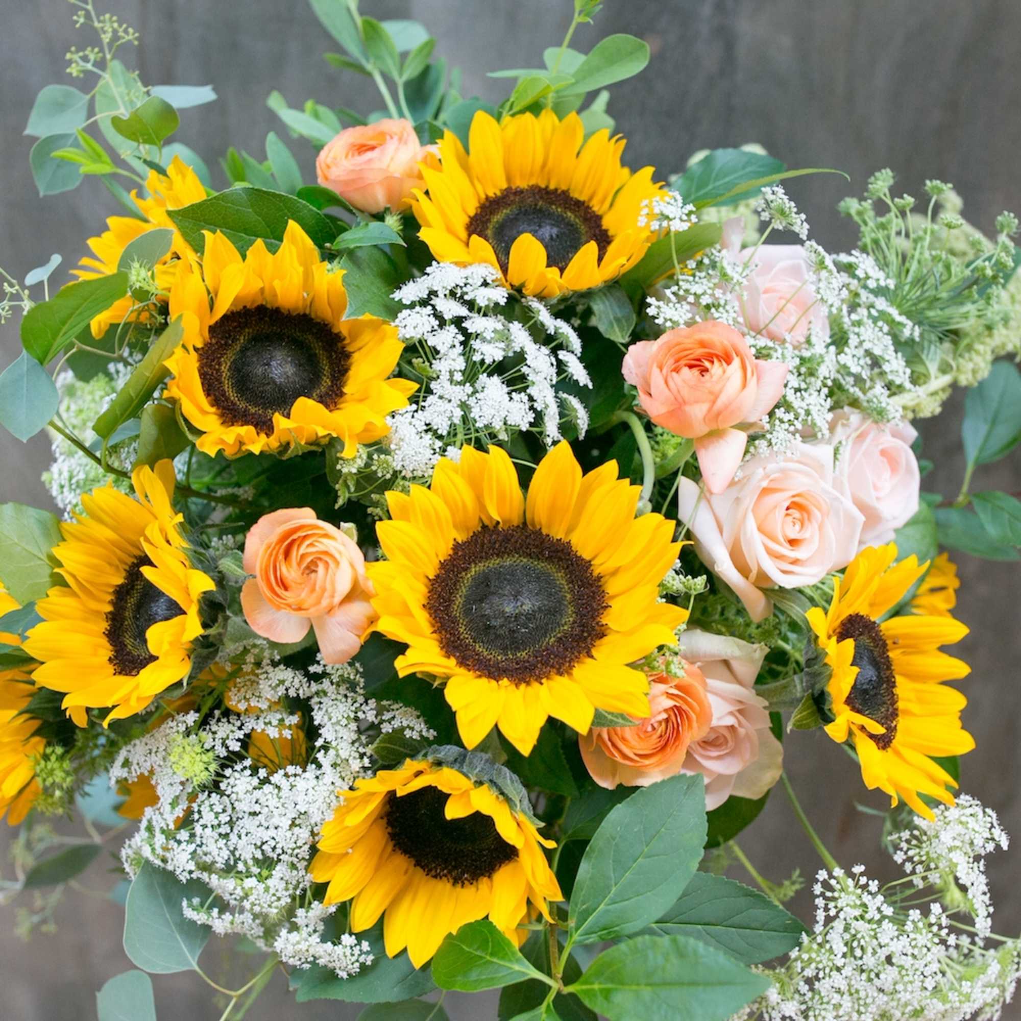 Bouquet of sunflowers and peach roses with white filler flowers