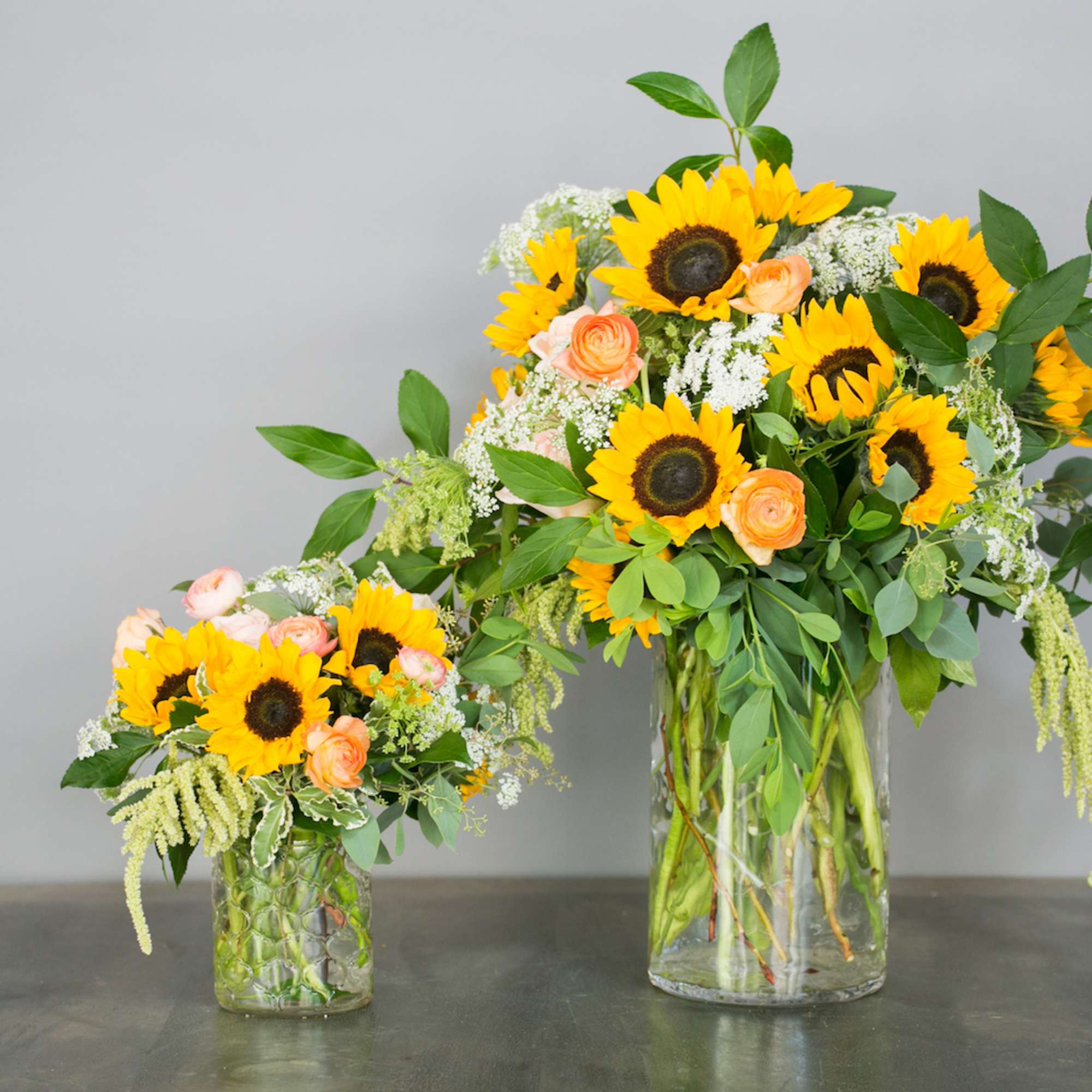 Sunflower and peach rose arrangements in clear glass vases