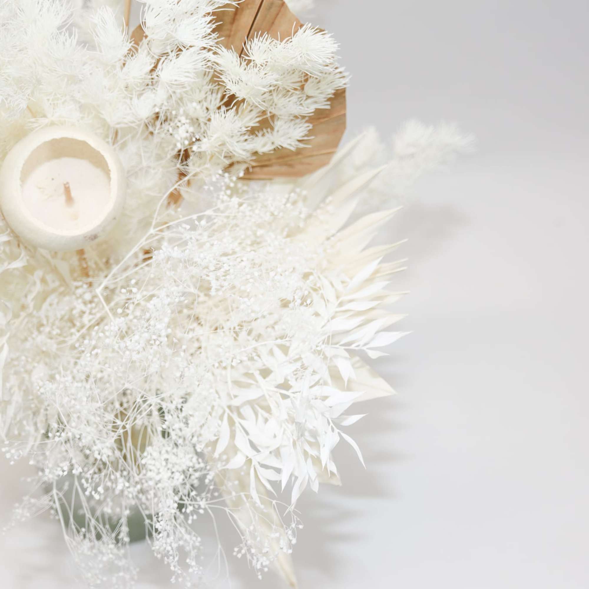 White dried floral arrangement with a small candle in the center