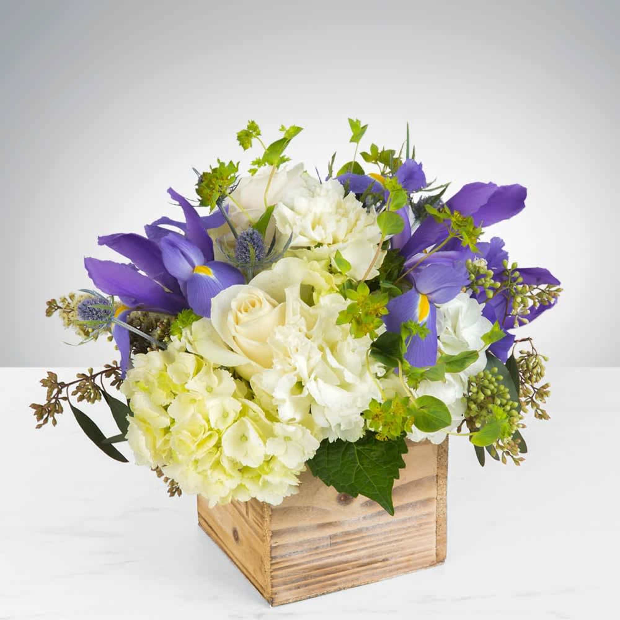 Creamy roses and ruffled white carnations meet vivid purple irises in a