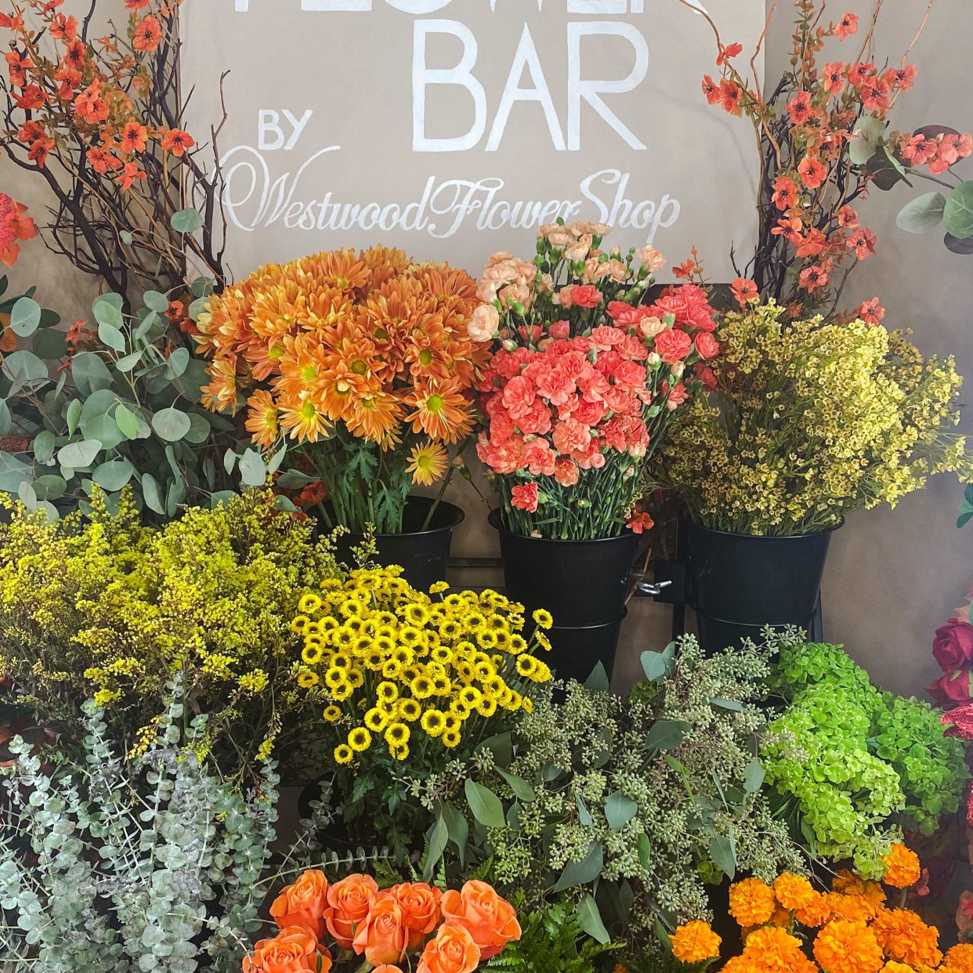 Assorted flower buckets with orange, yellow, pink, and green blooms