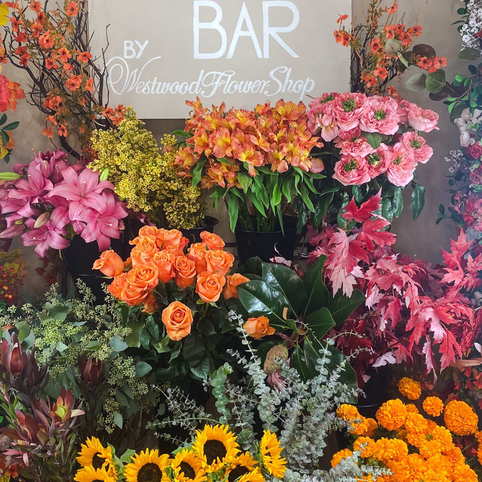 Assorted flower arrangements in buckets with a "FLOWER BAR" sign