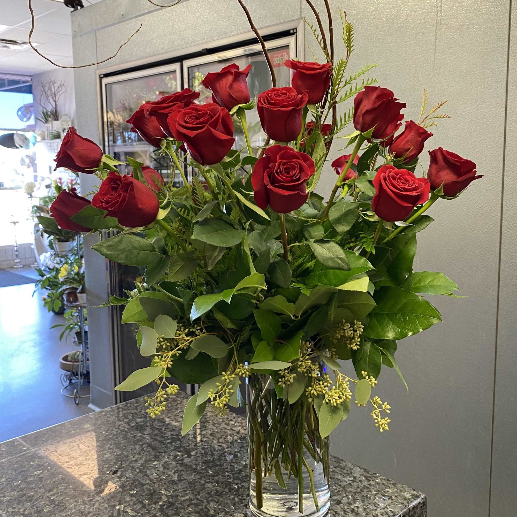 Red roses arranged in a clear glass vase with greenery