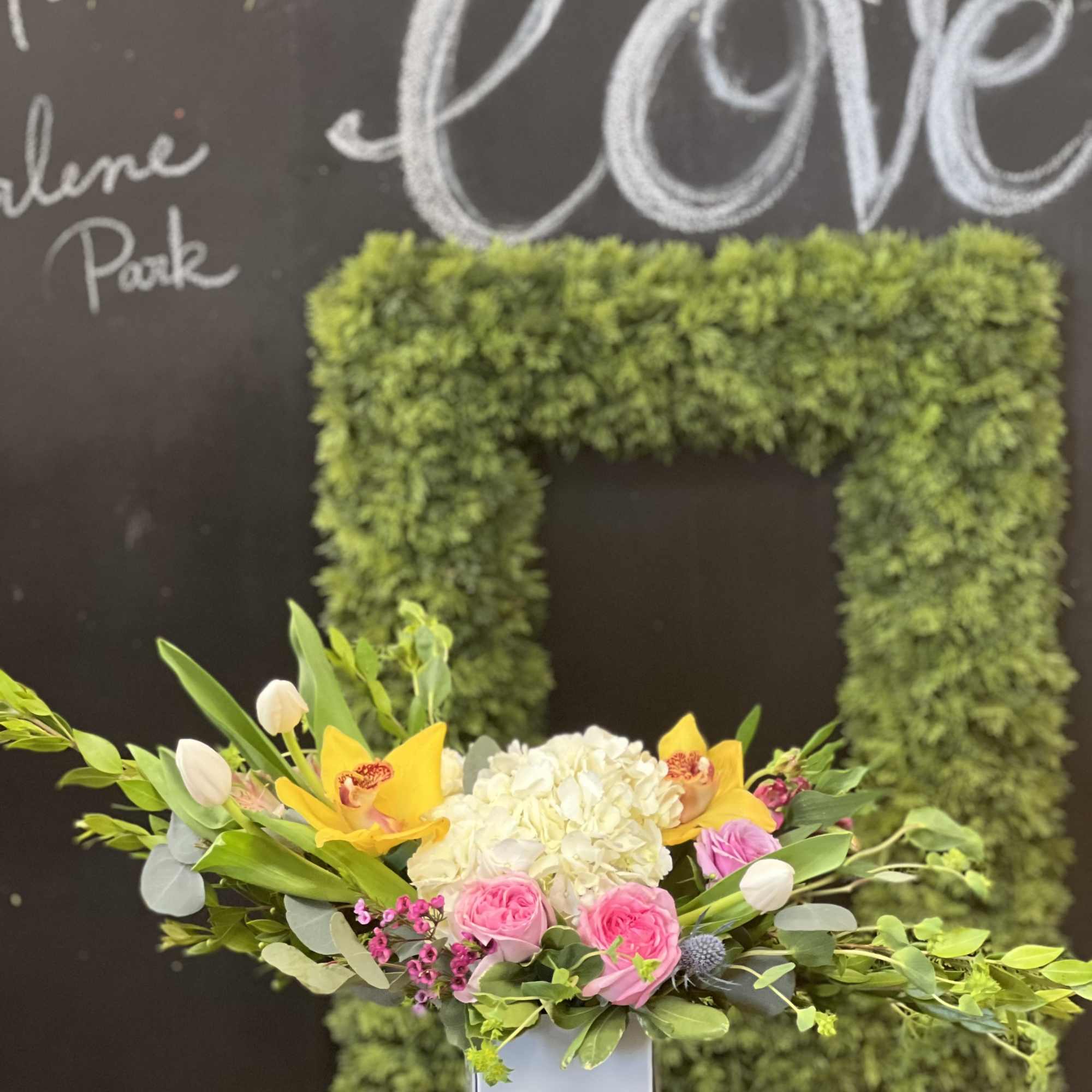 Mixed floral arrangement in a white vase with pink roses and yellow orchids