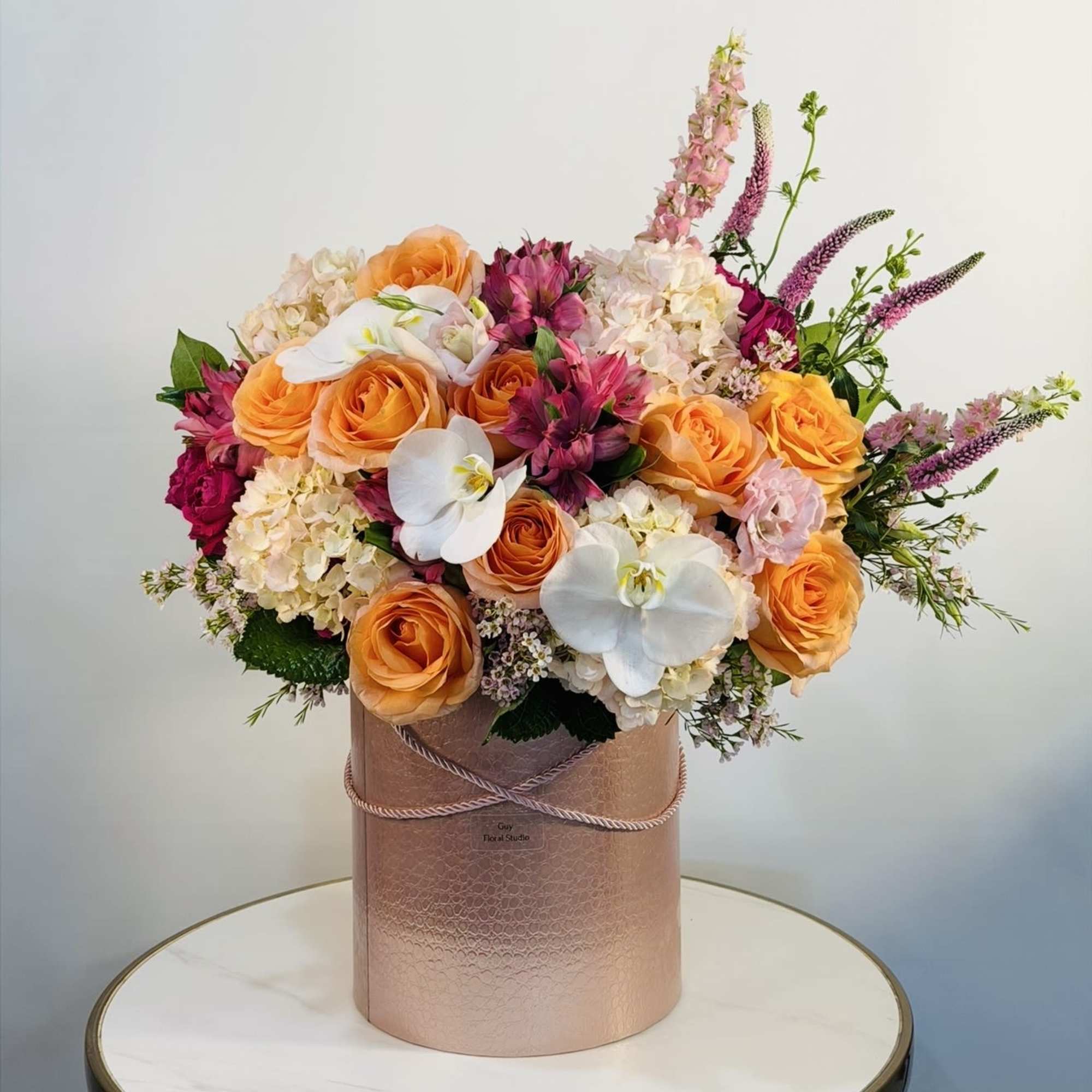 The Golden Sunset Orchid Arrangement is a stunning luxury floral design featuring