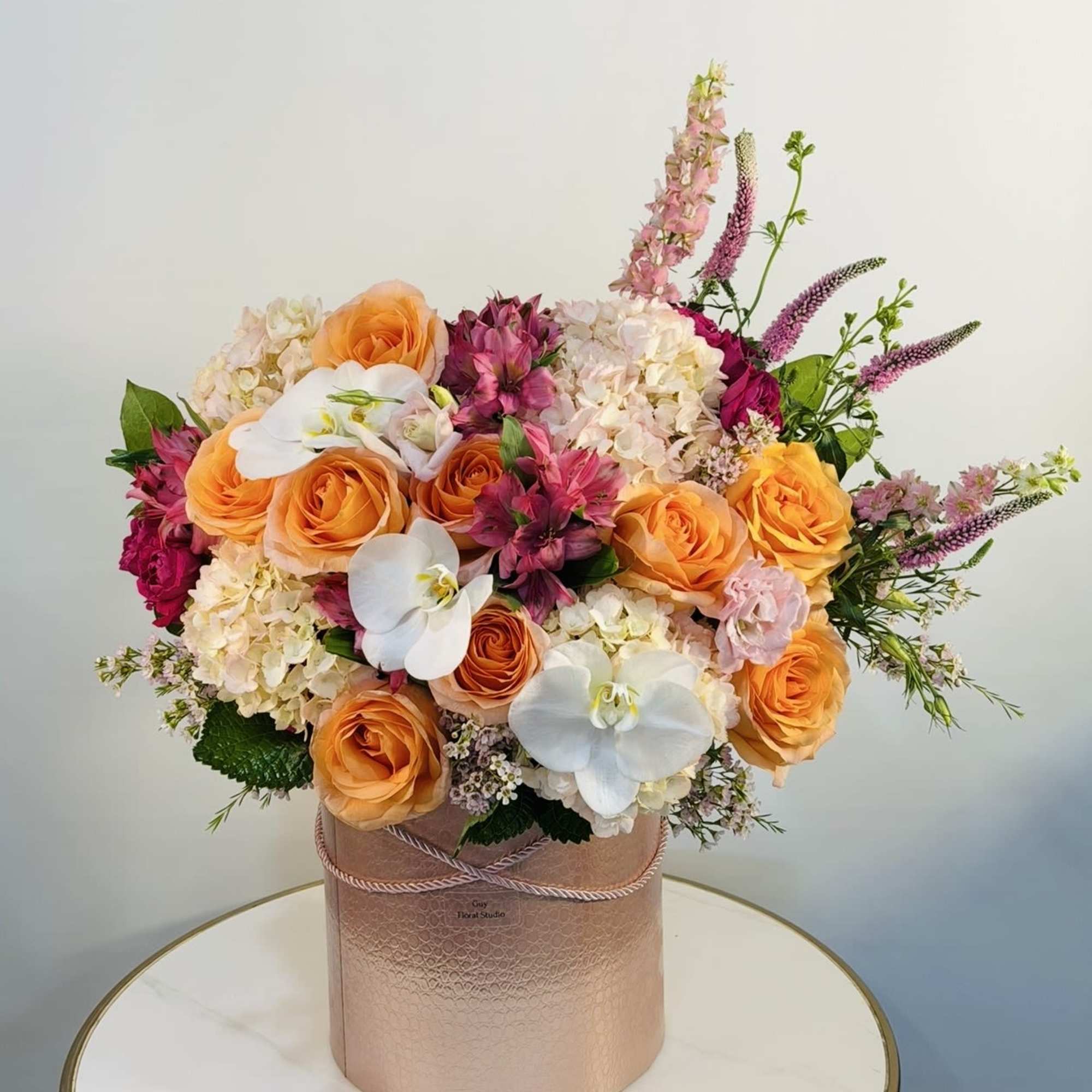 The Golden Sunset Orchid Arrangement is a stunning luxury floral design featuring