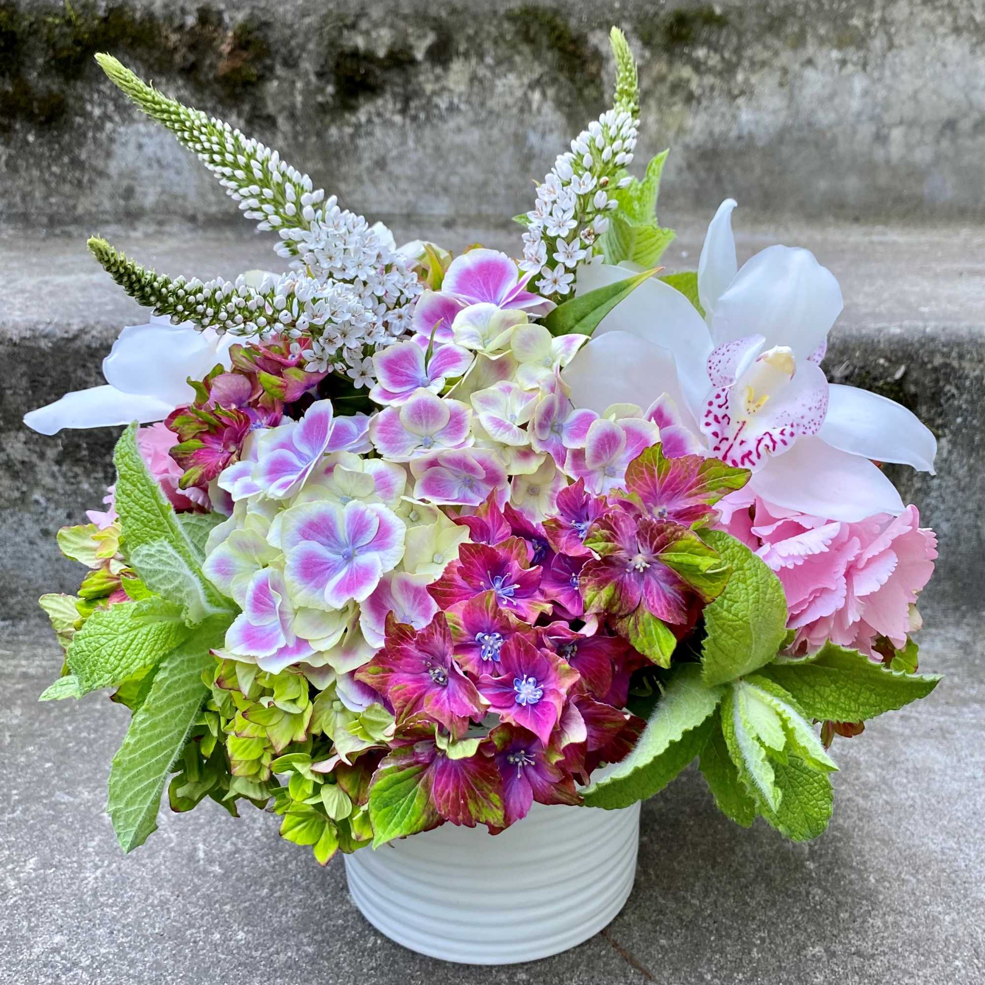 Colorful bouquet of hydrangeas and orchids in a white vase