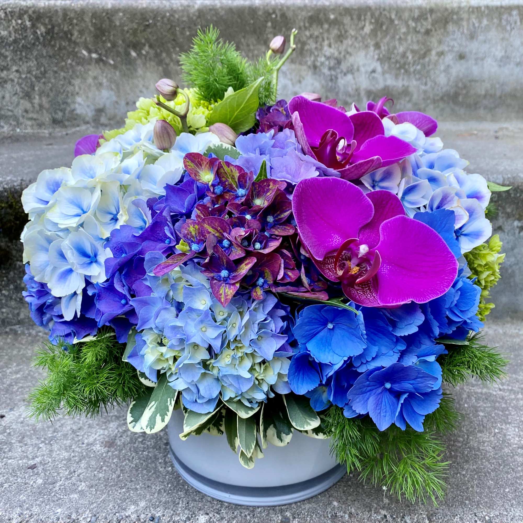 Blue and purple floral arrangement in a gray pot