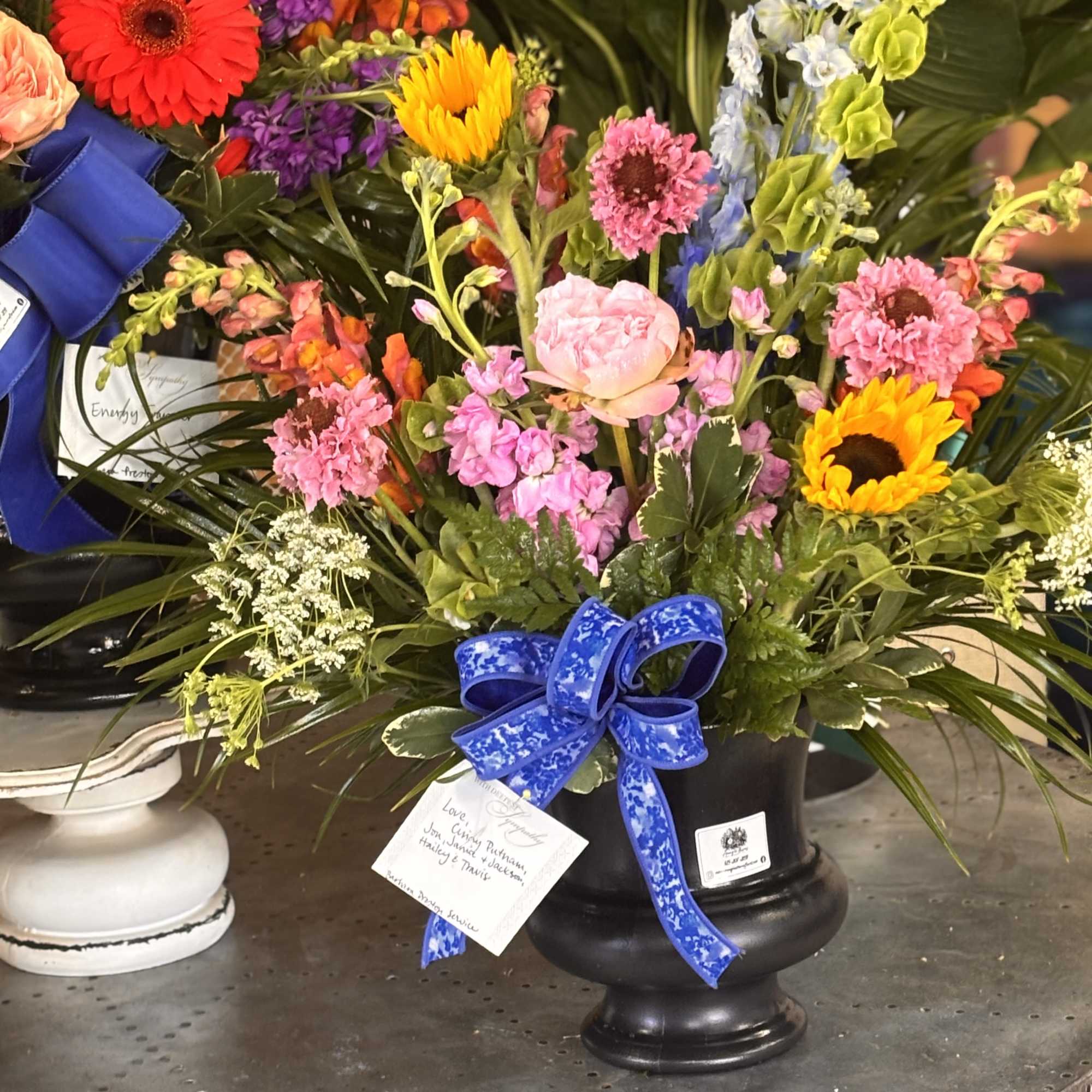 Bright, uplifted blooms in a black urn create a comforting yet celebratory