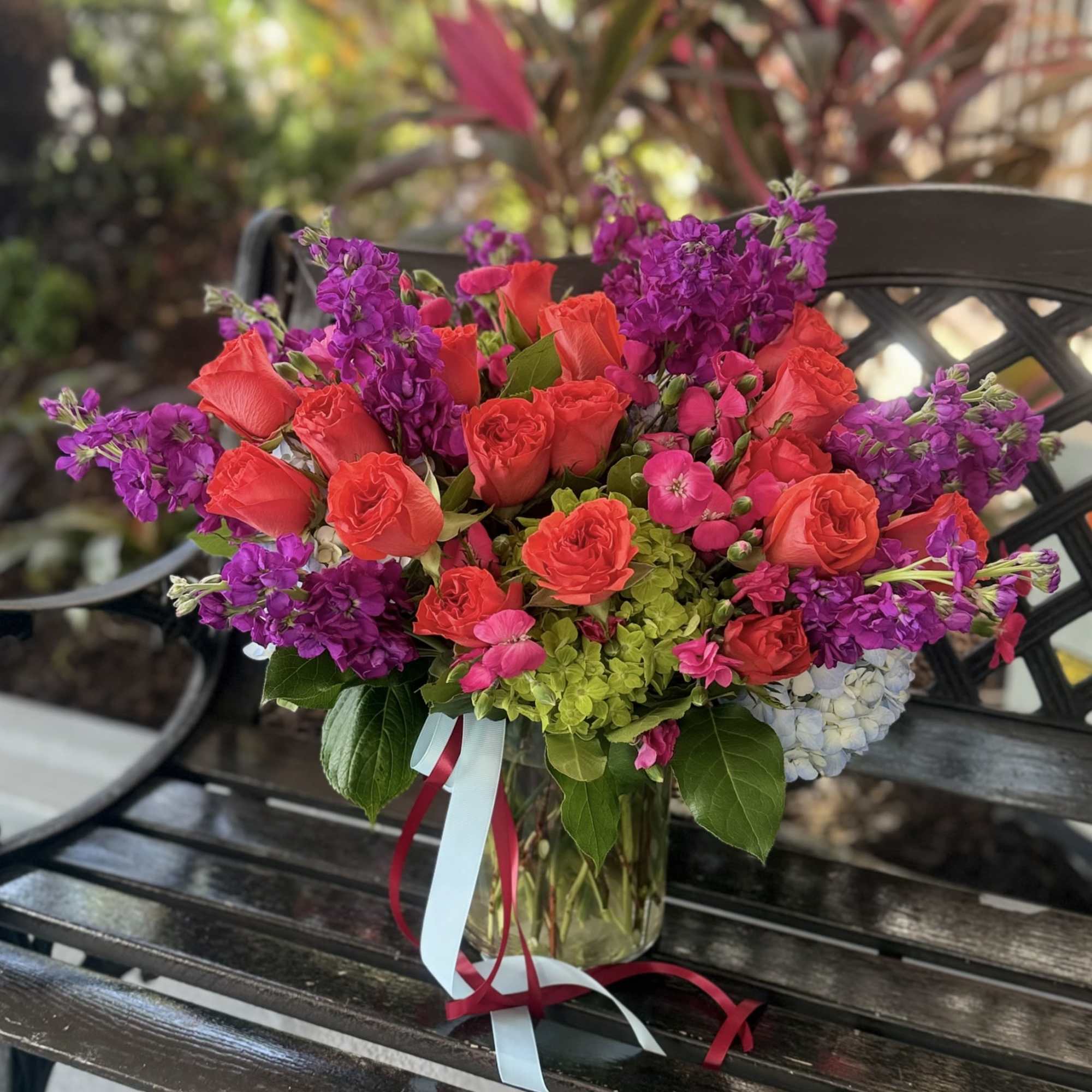 Vivid magenta roses and towering purple stock give this flower arrangement an