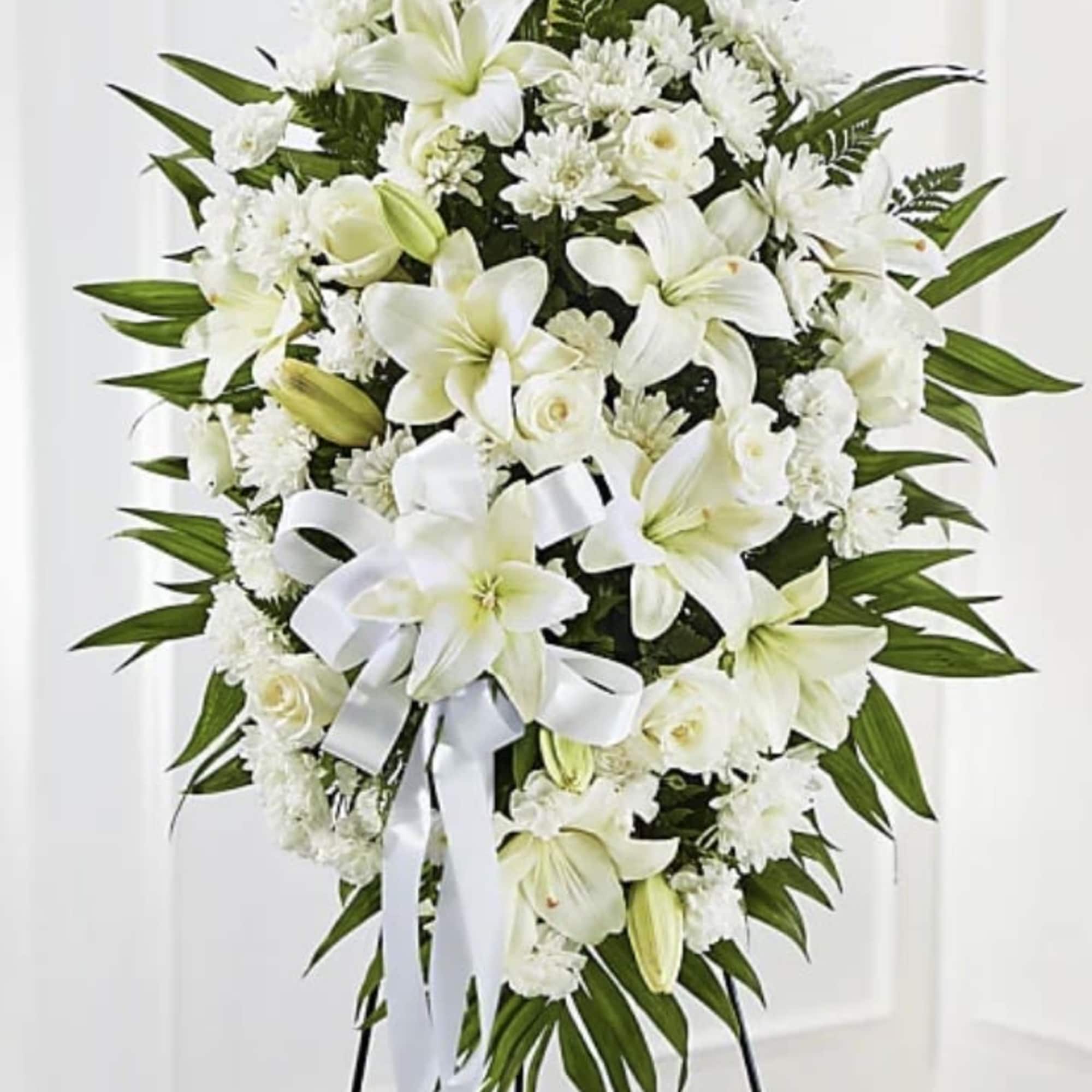 White funeral spray with lilies, roses, and chrysanthemums on a stand
