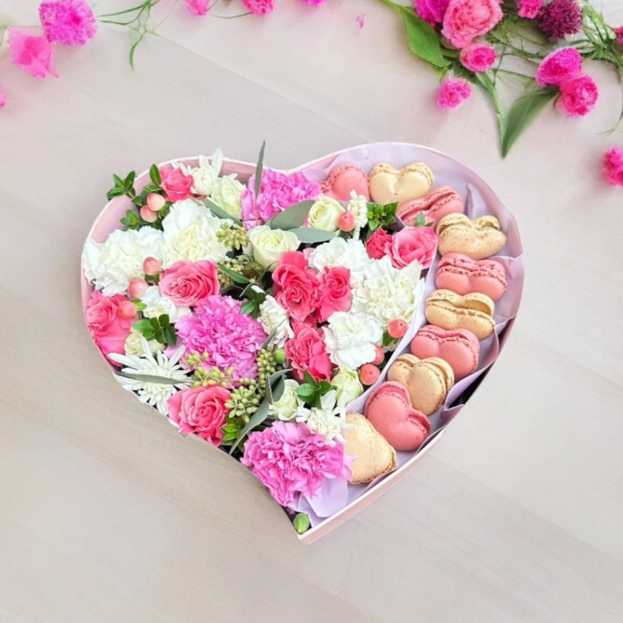 Heart-shaped box with pink and white flowers and heart-shaped macarons
