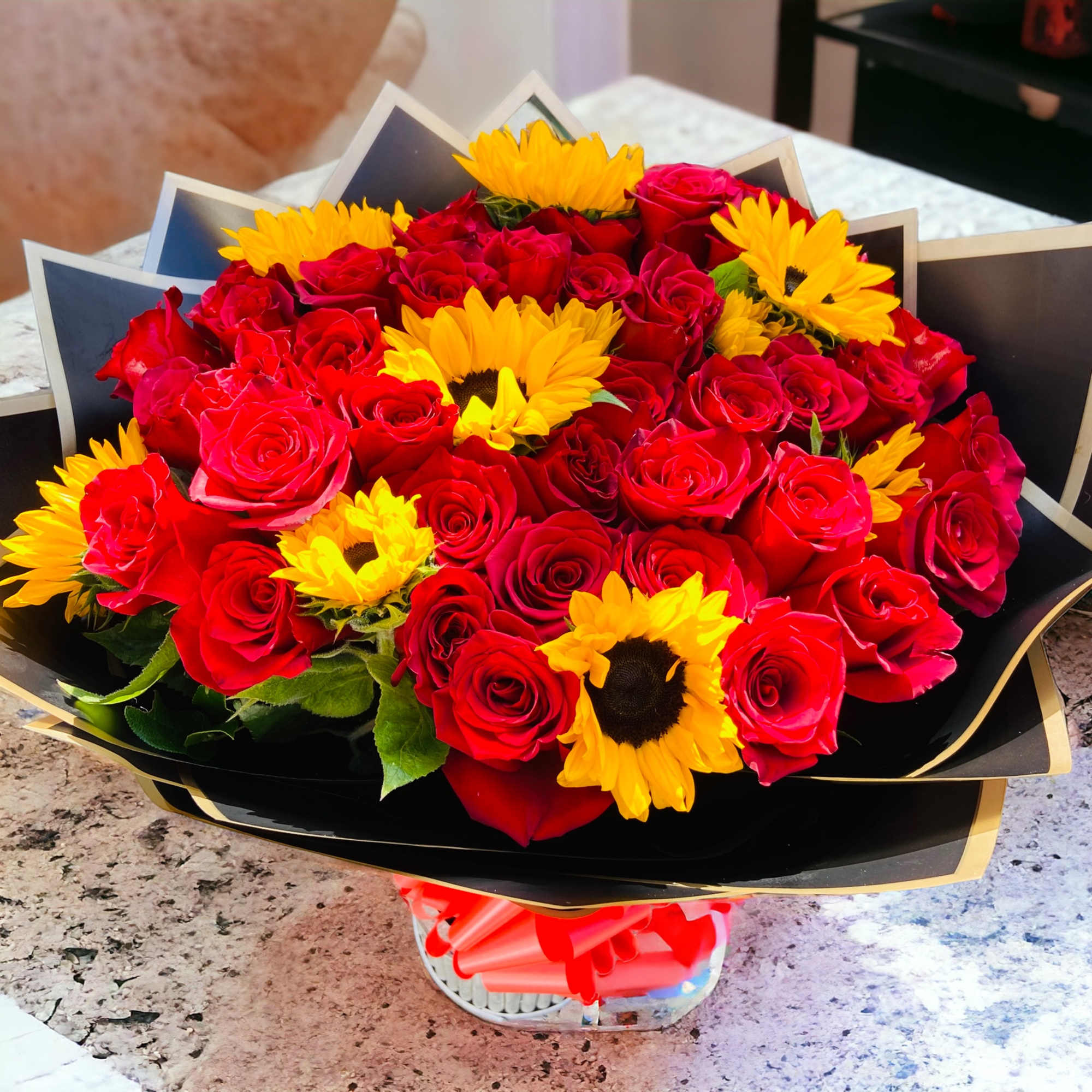 Bouquet of red roses and yellow sunflowers wrapped in black paper