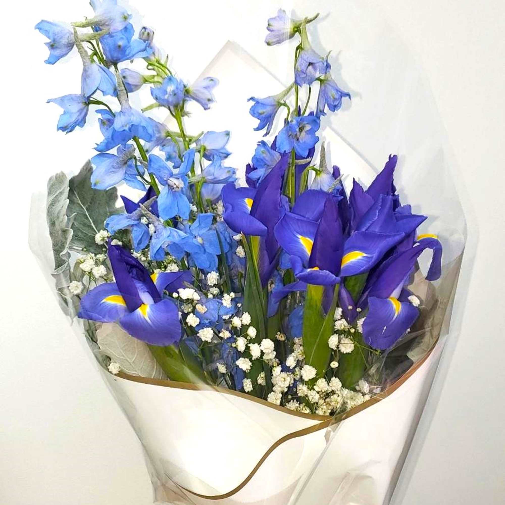 Bouquet of blue irises and light blue delphinium wrapped in white paper