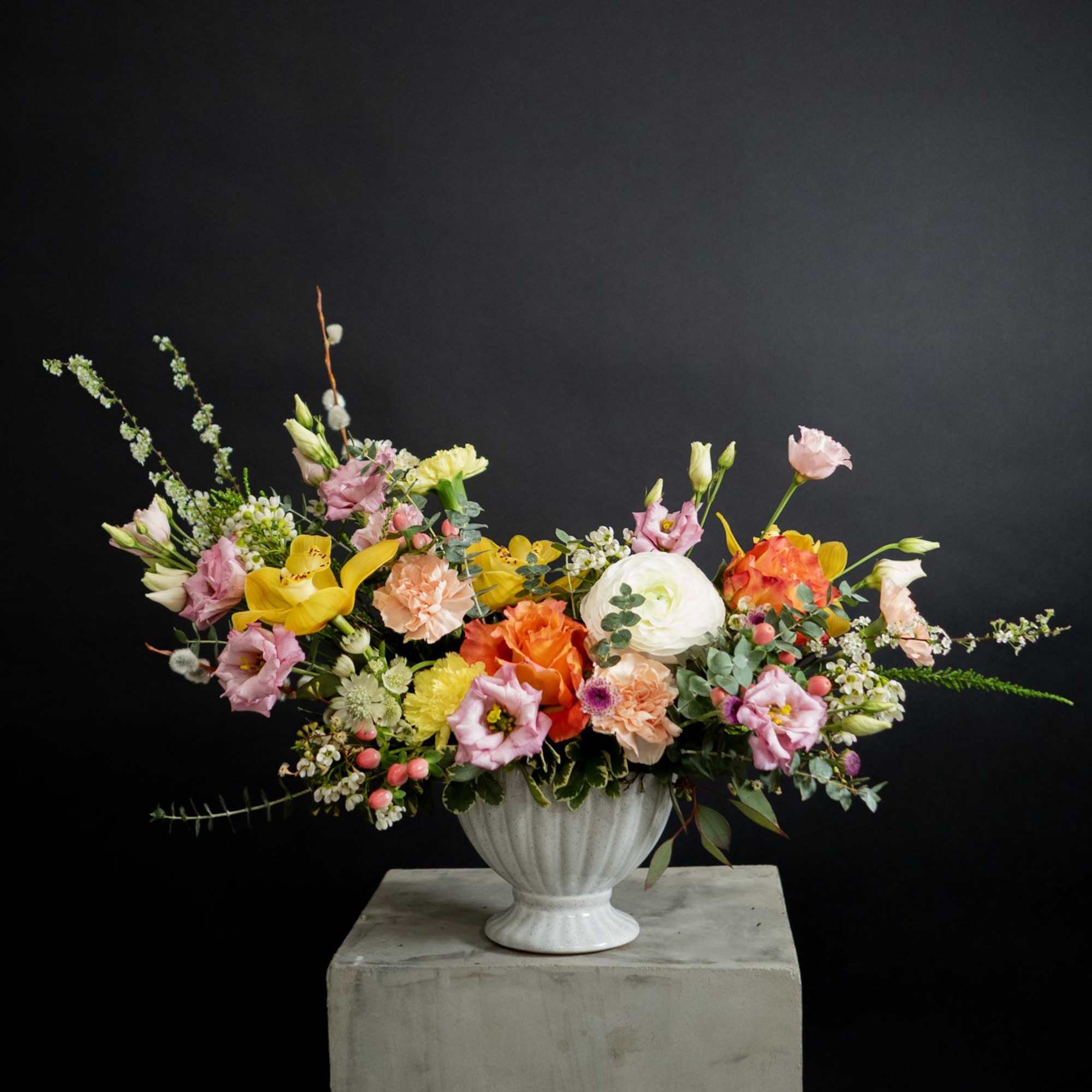 Colorful mixed flower arrangement in a white pedestal vase