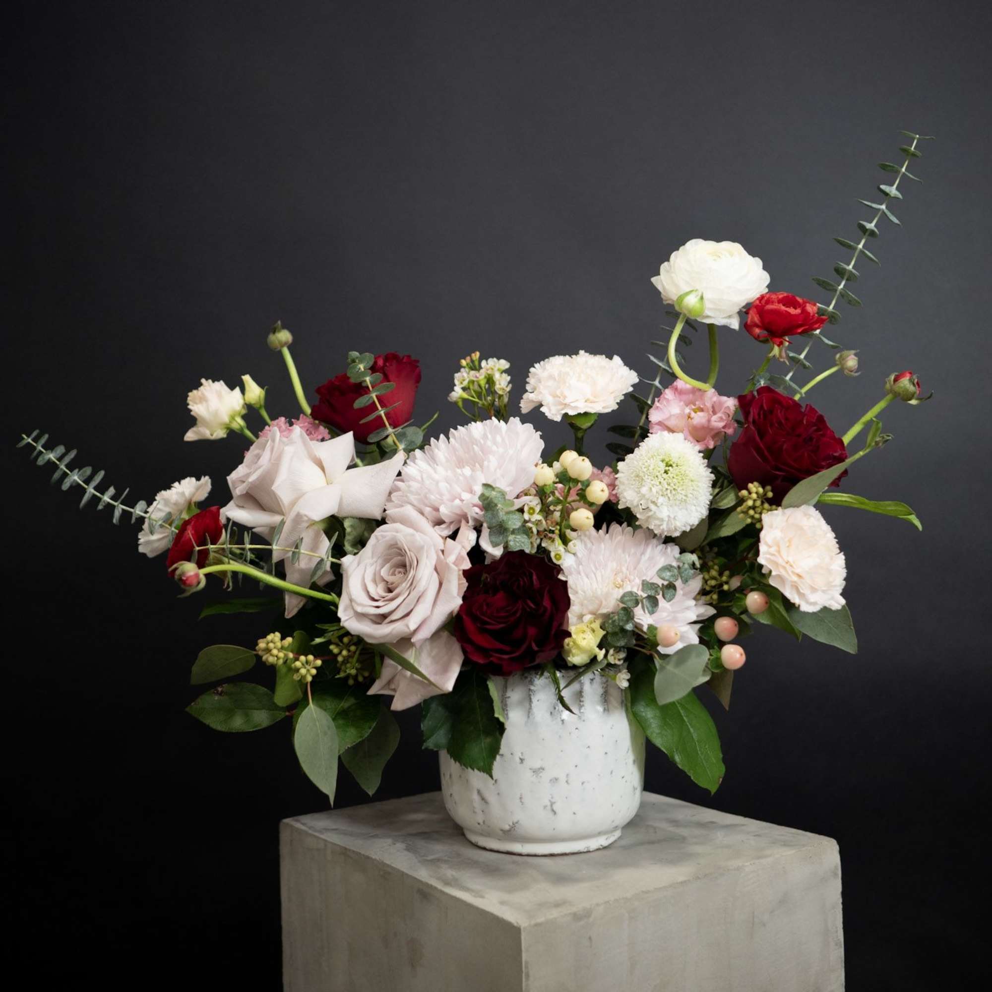 Mixed bouquet of roses and carnations in a white vase