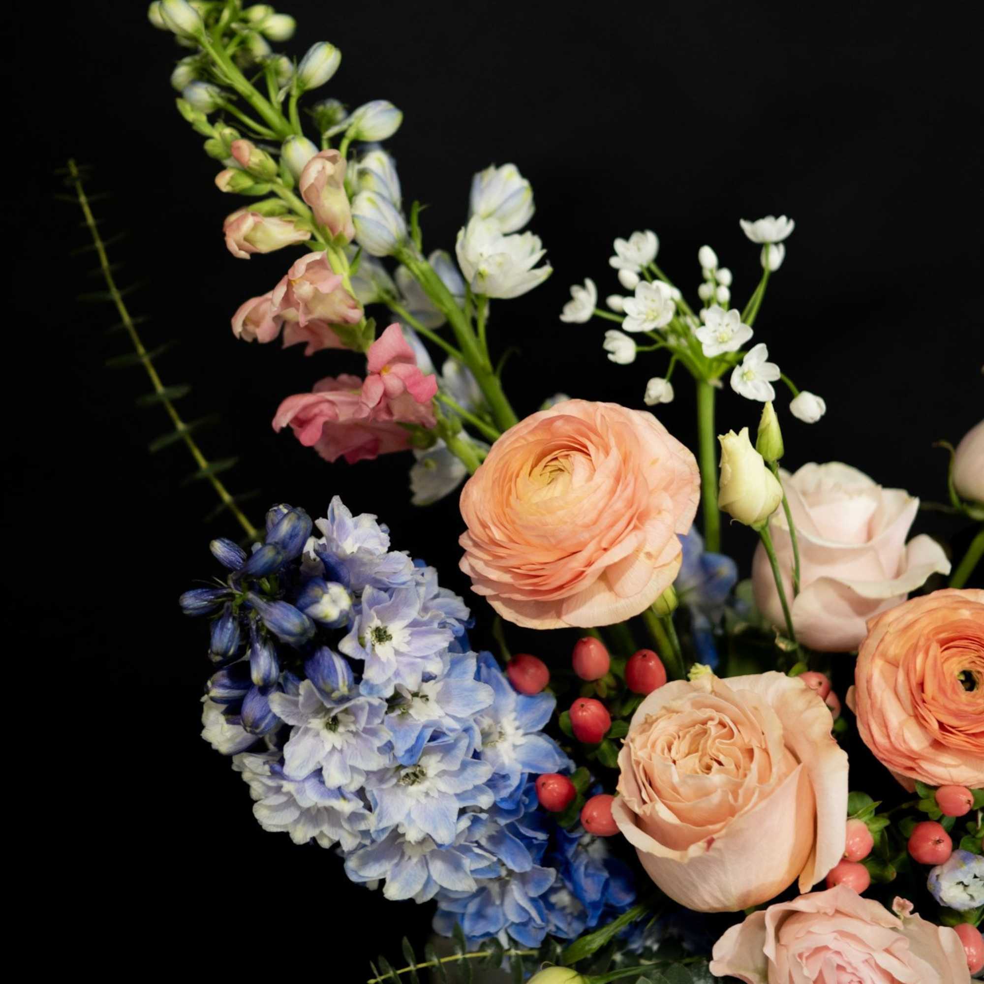 Bouquet of peach roses, blue hydrangeas, and white blossoms