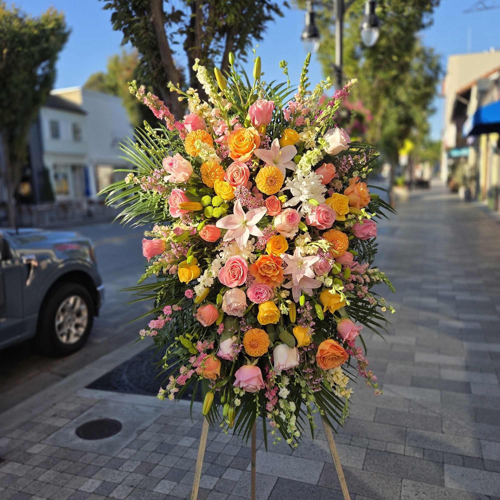 Large standing floral spray with pink, orange, and yellow blooms on an easel