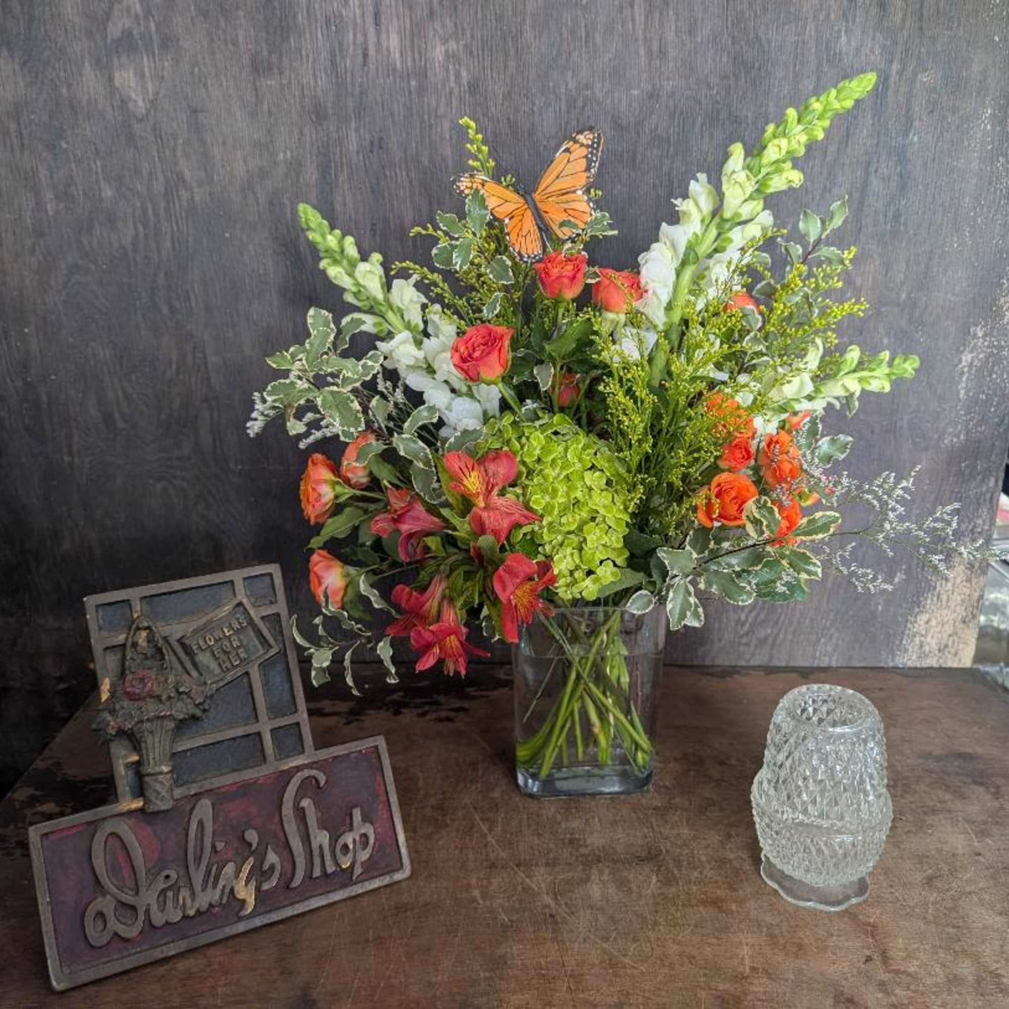 Bright orange roses and playful butterfly picks give this mixed-color bouquet a