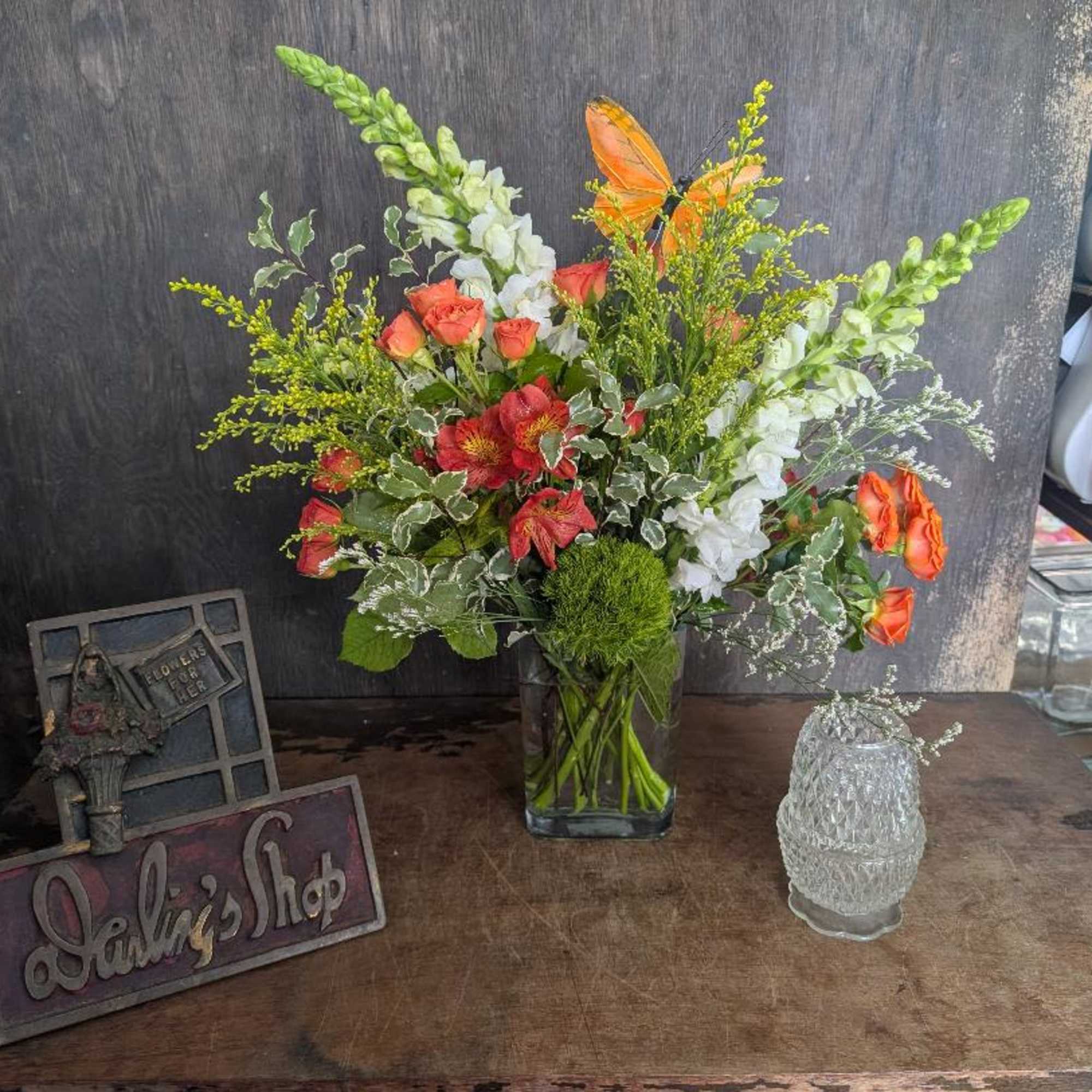 Bright orange roses and playful butterfly picks give this mixed-color bouquet a