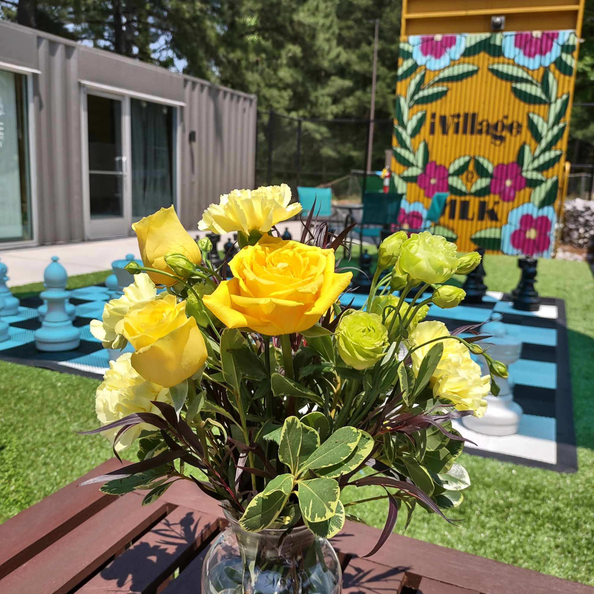 Yellow roses and green blooms in a clear glass vase
