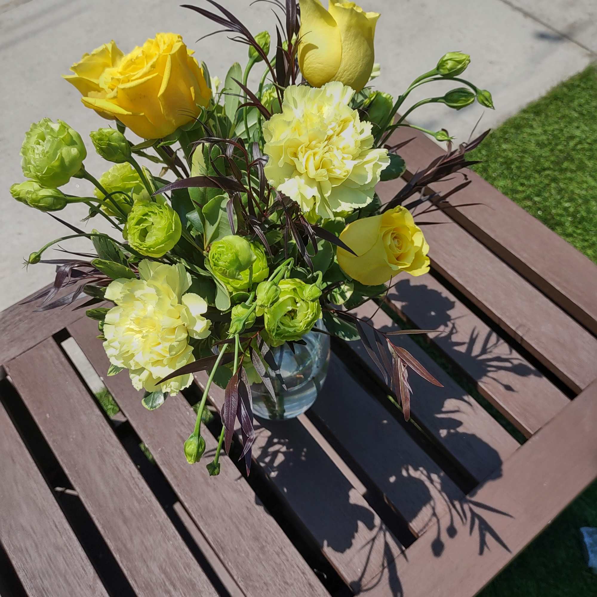 Yellow roses and carnations in a glass vase on a table